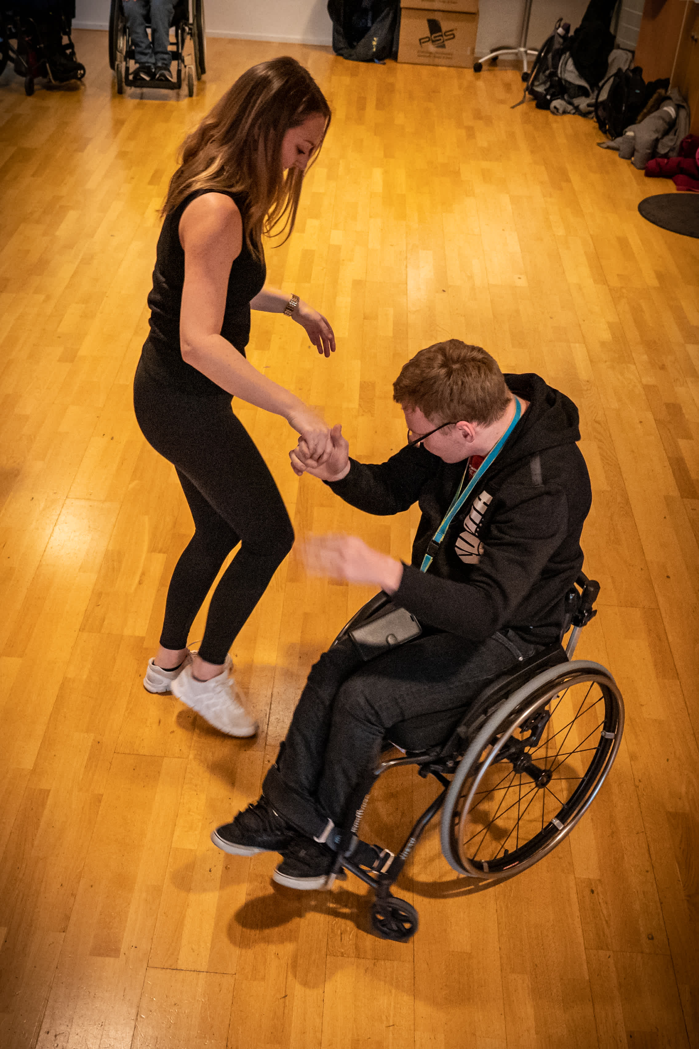 En ung man i rullstol dansar med en ung kvinna utan rullstol.