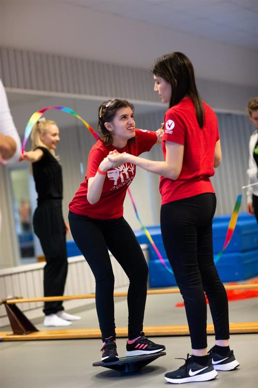 En gymnast i Alla kan gympa får hjälp av en ledare att hålla balansen.