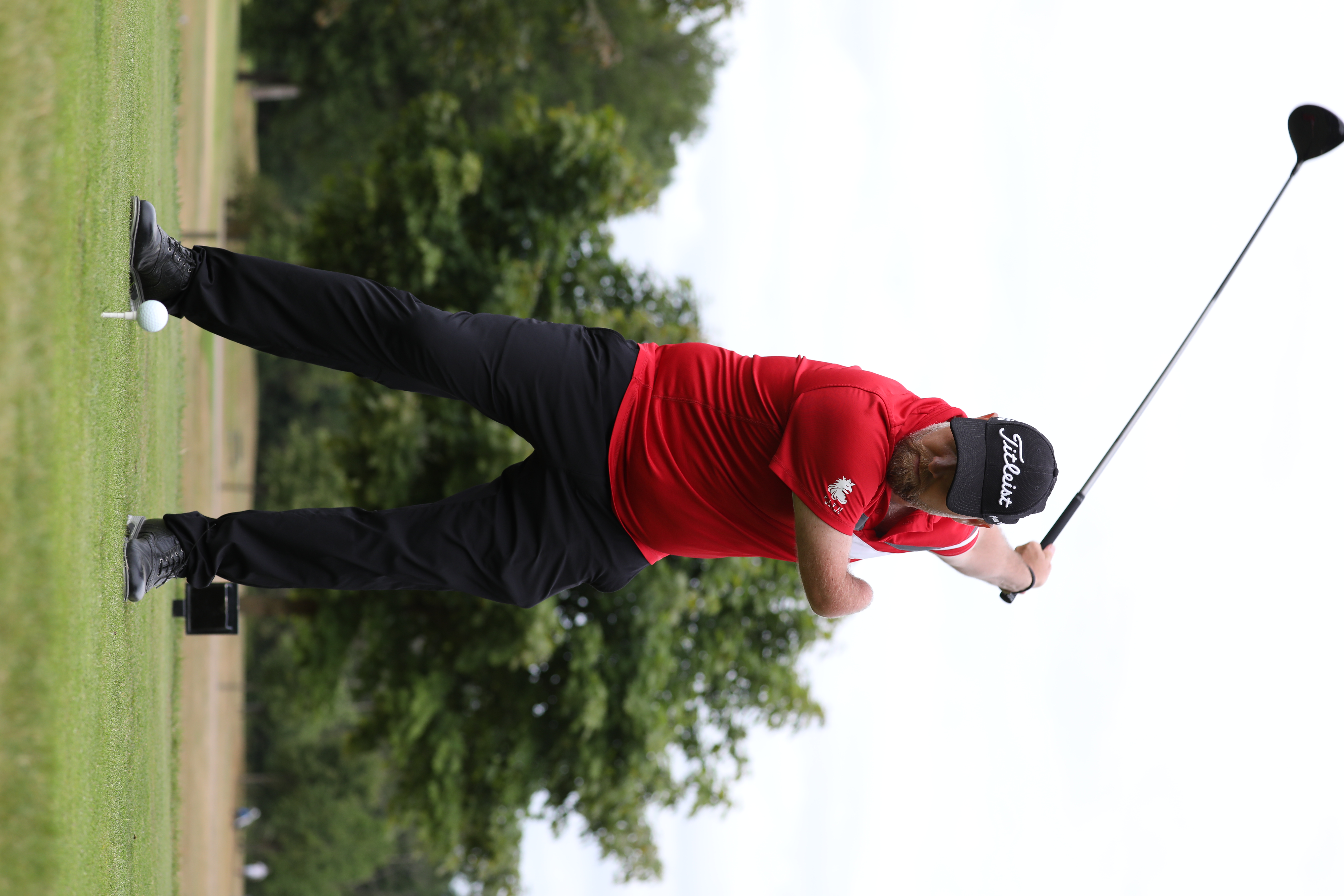 Man med en arm slår ut golfbollen med en klubba.