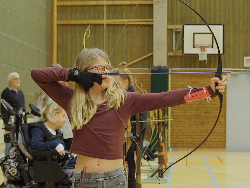 En flicka siktar med ena ögat stängt.