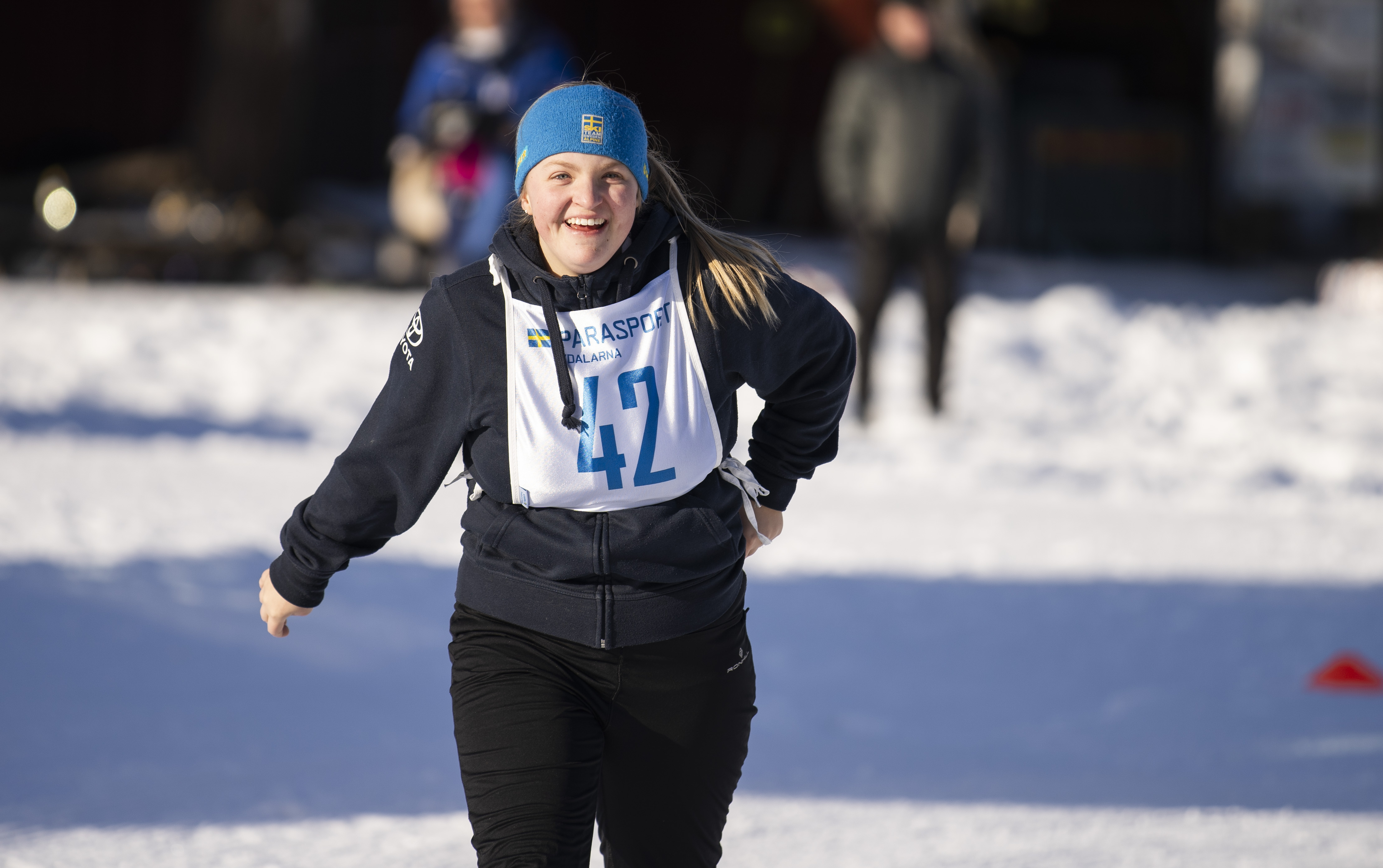 Foto, utomhus. En ung tjej i träningskläder är ute och joggar i snön.