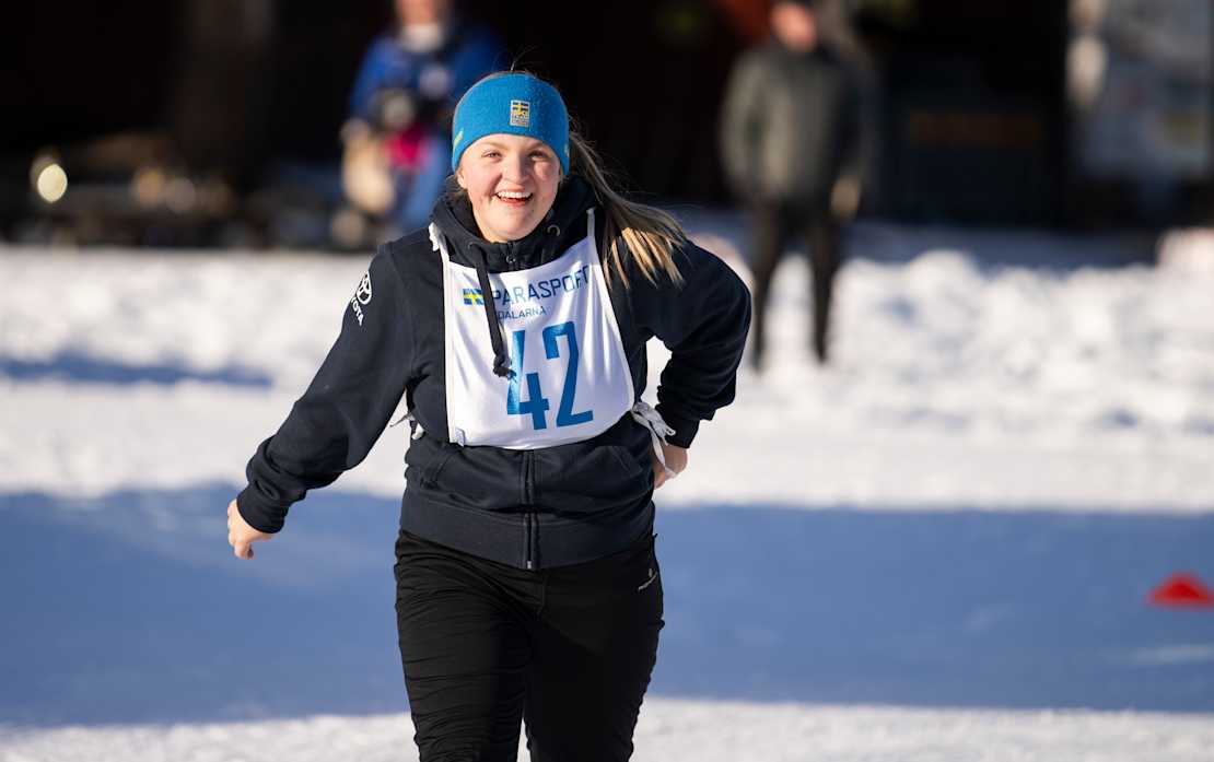 Foto, utomhus. En ung tjej i träningskläder är ute och joggar i snön.