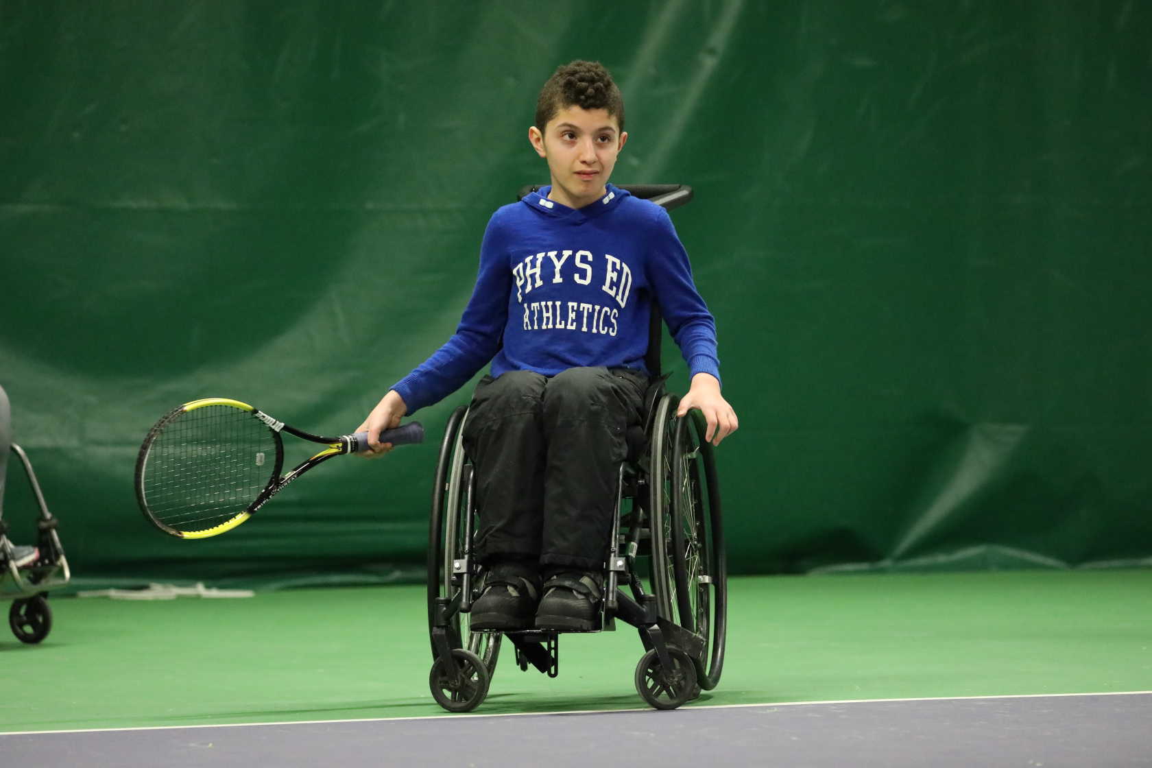 Pojke i rullstol redo att slå tennisbollen.