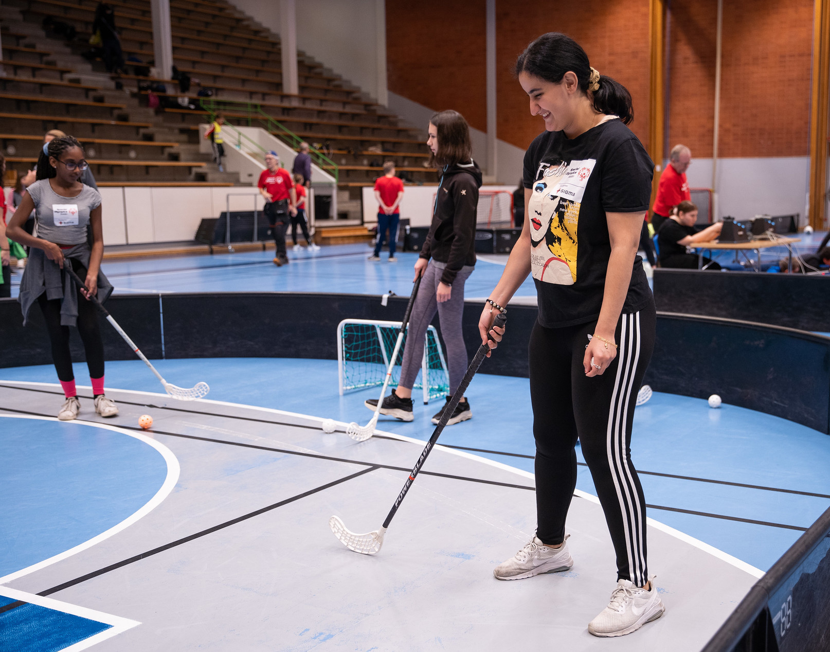Tjej tränar innebandy i en rink, tillsammans med andra tjejer.