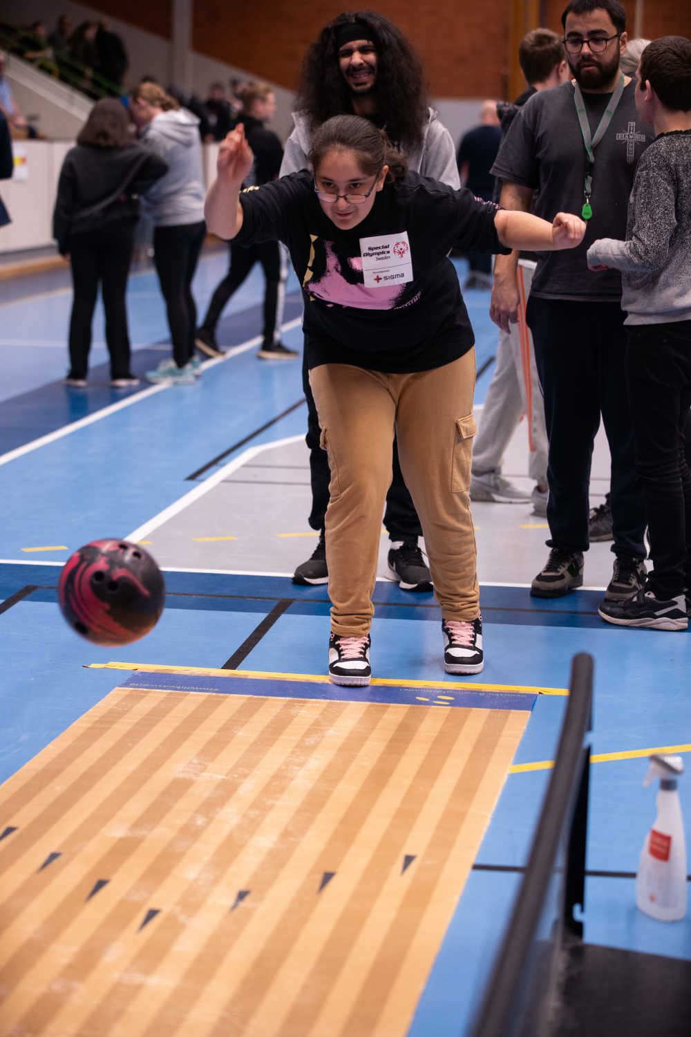 Tjej har precis kastat klotet ut på bowlingbanan, klotet är på bilden fortfarande i luften.