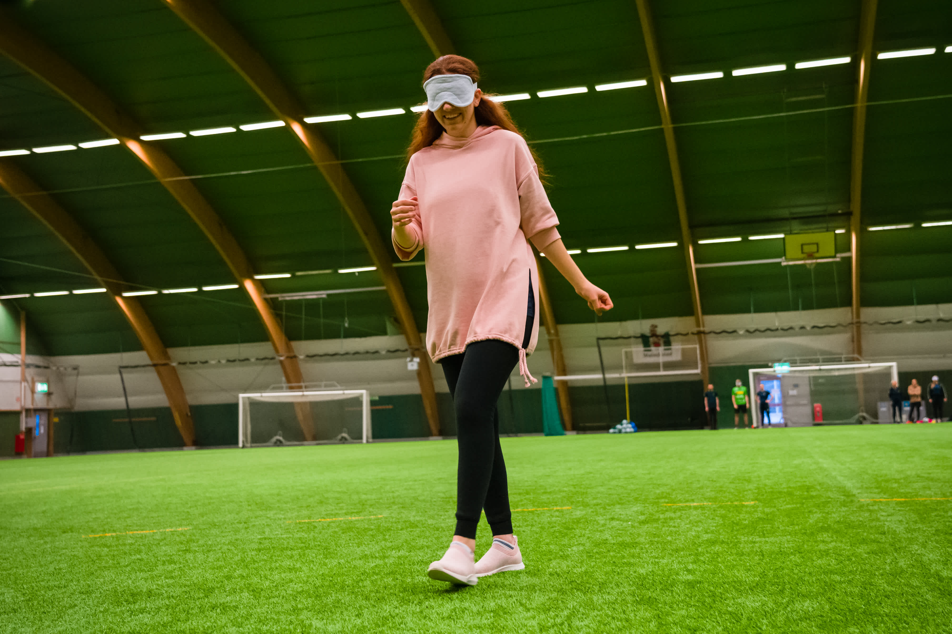 Tjej med ögonbindel lär känna fotbollsplanen genom att gå över den.