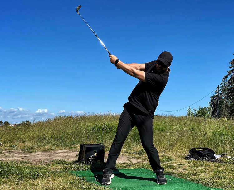 Torbjörn slår en boll från tee på ett av hålen på golfbanan.