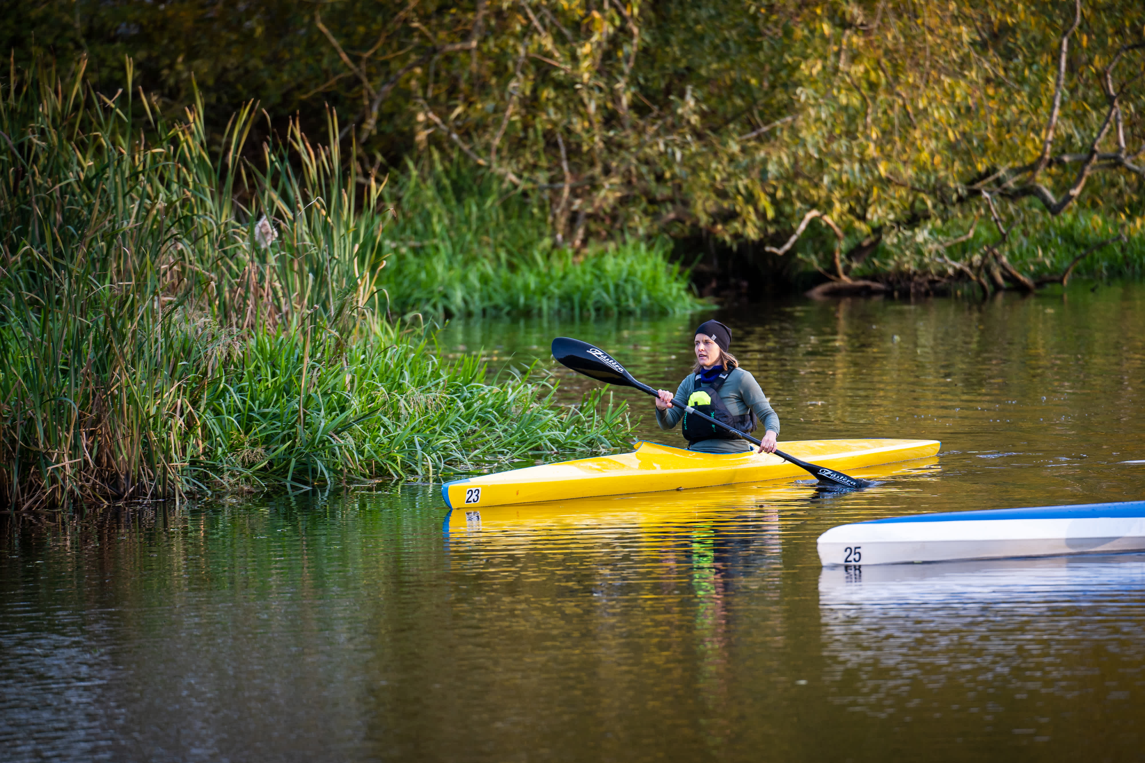 Kvinna ute och paddlar i en gul kanot.