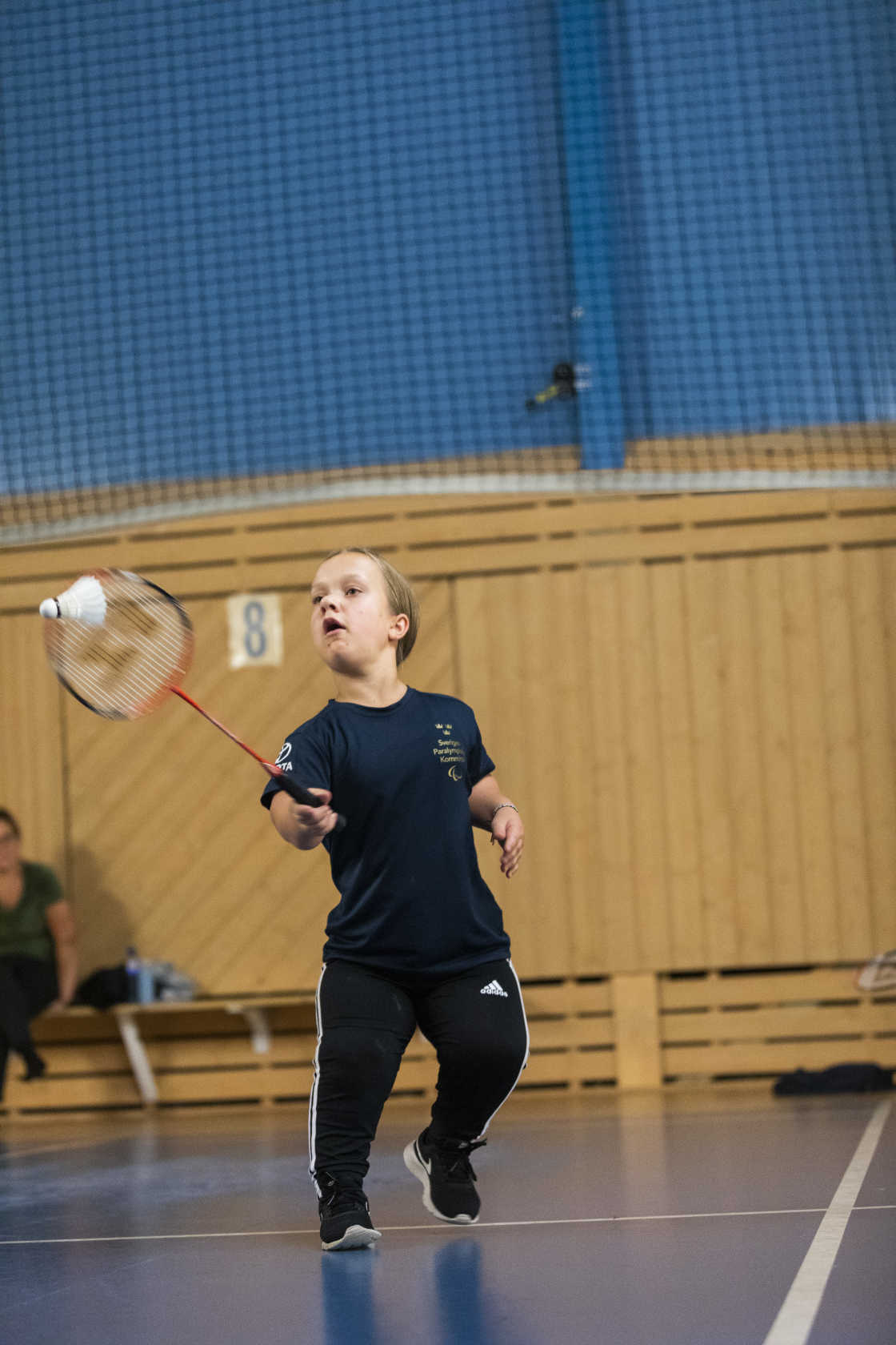 En tjej med kortväxthet slår iväg badmintonfjädern.