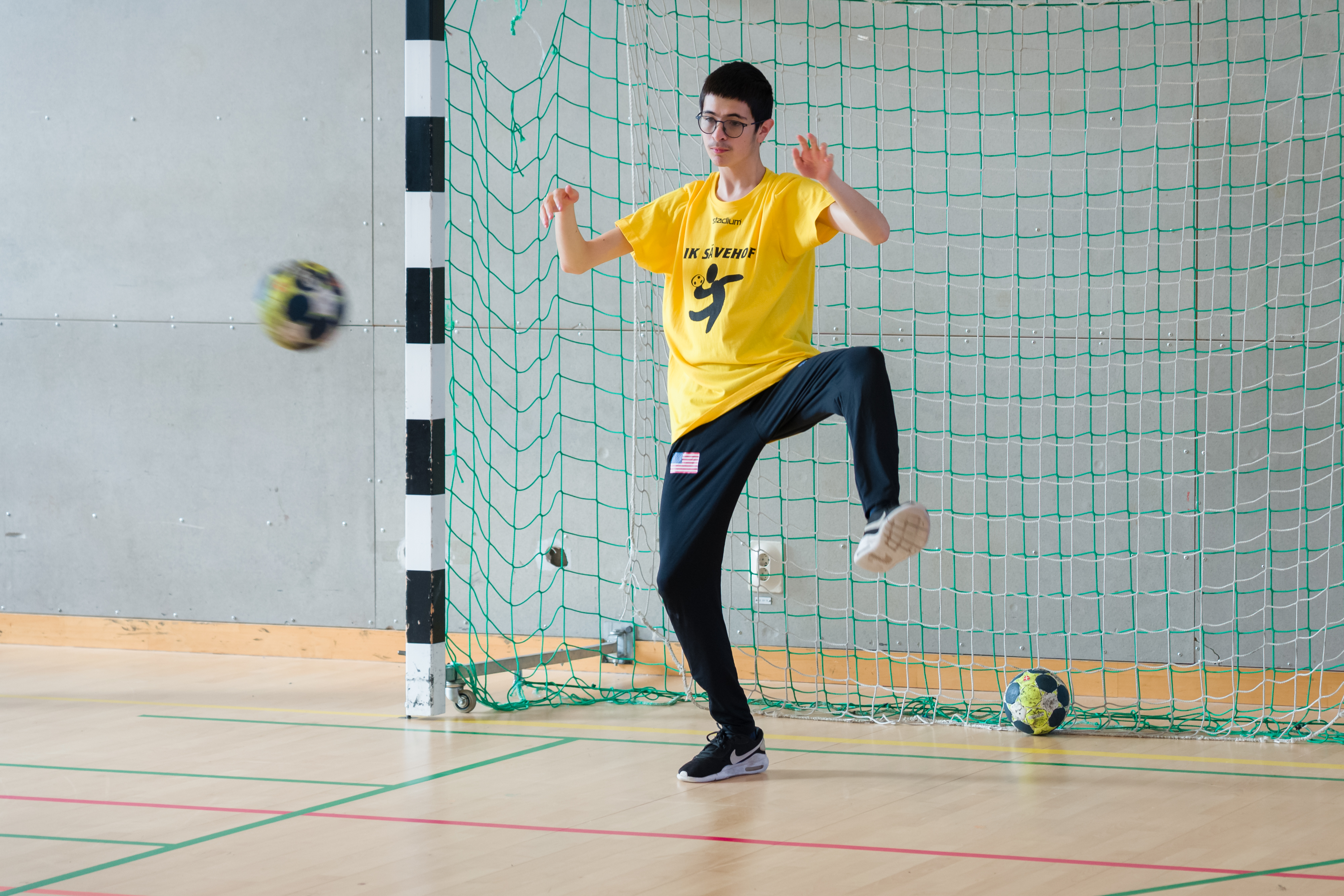 Kille står i mål, redo att fånga en boll som kommer flygande.