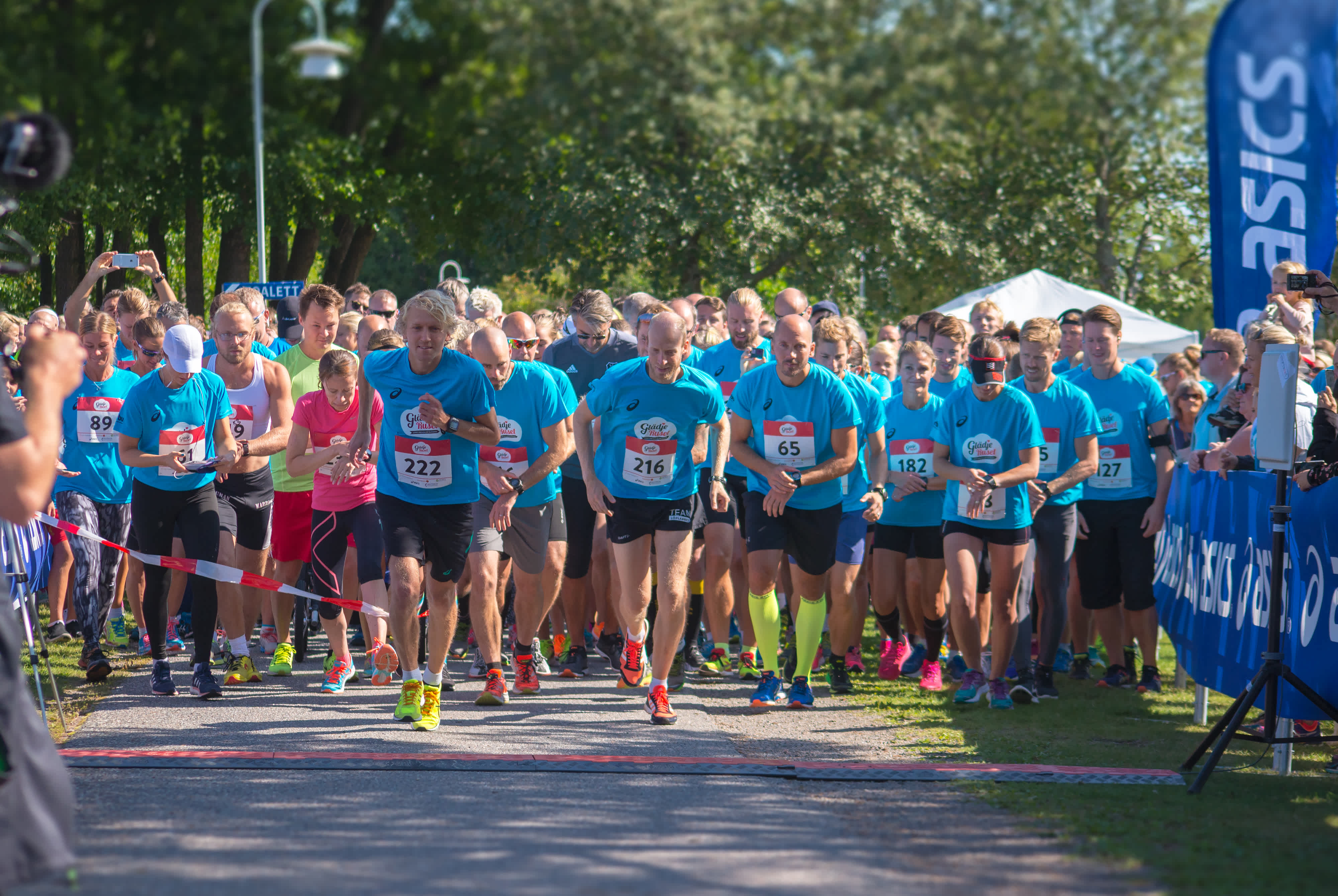 Många deltagare i blå tröjor står på startlinjen inför loppet.