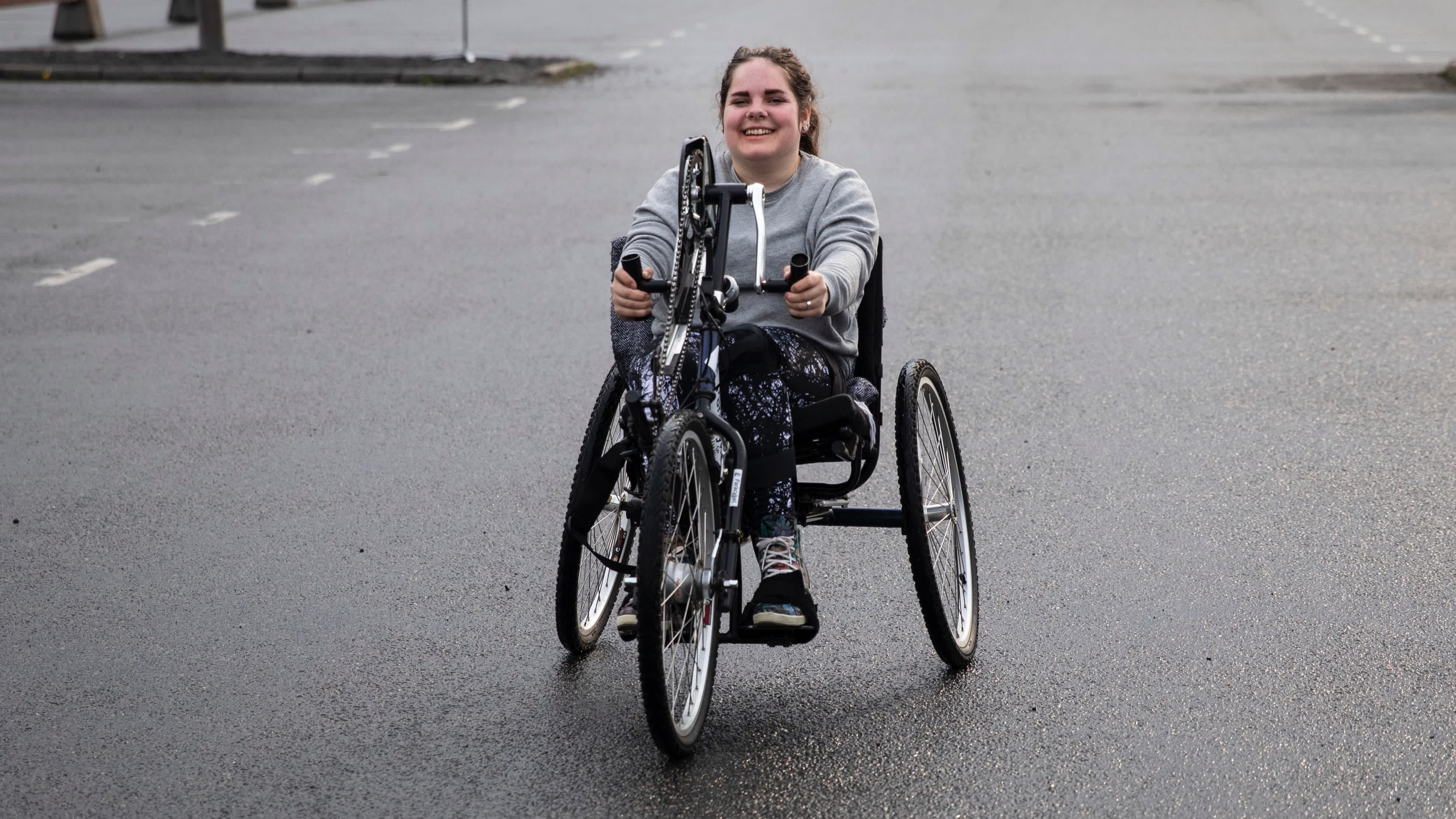 En kvinna provar en handcykel på en parkeringsplats.