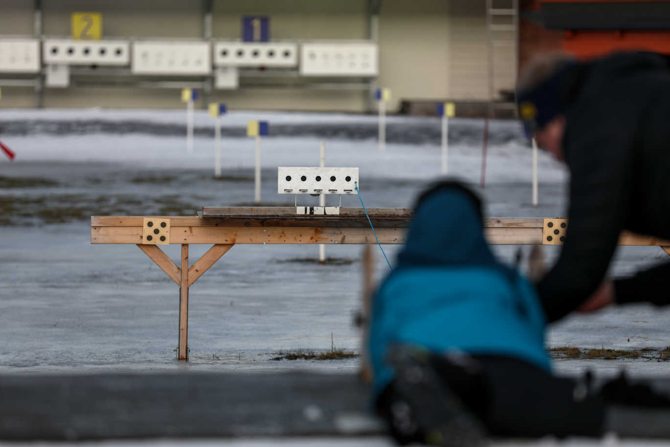 Ett barn ligger ner på mage och får hjälp av en ledare med geväret.