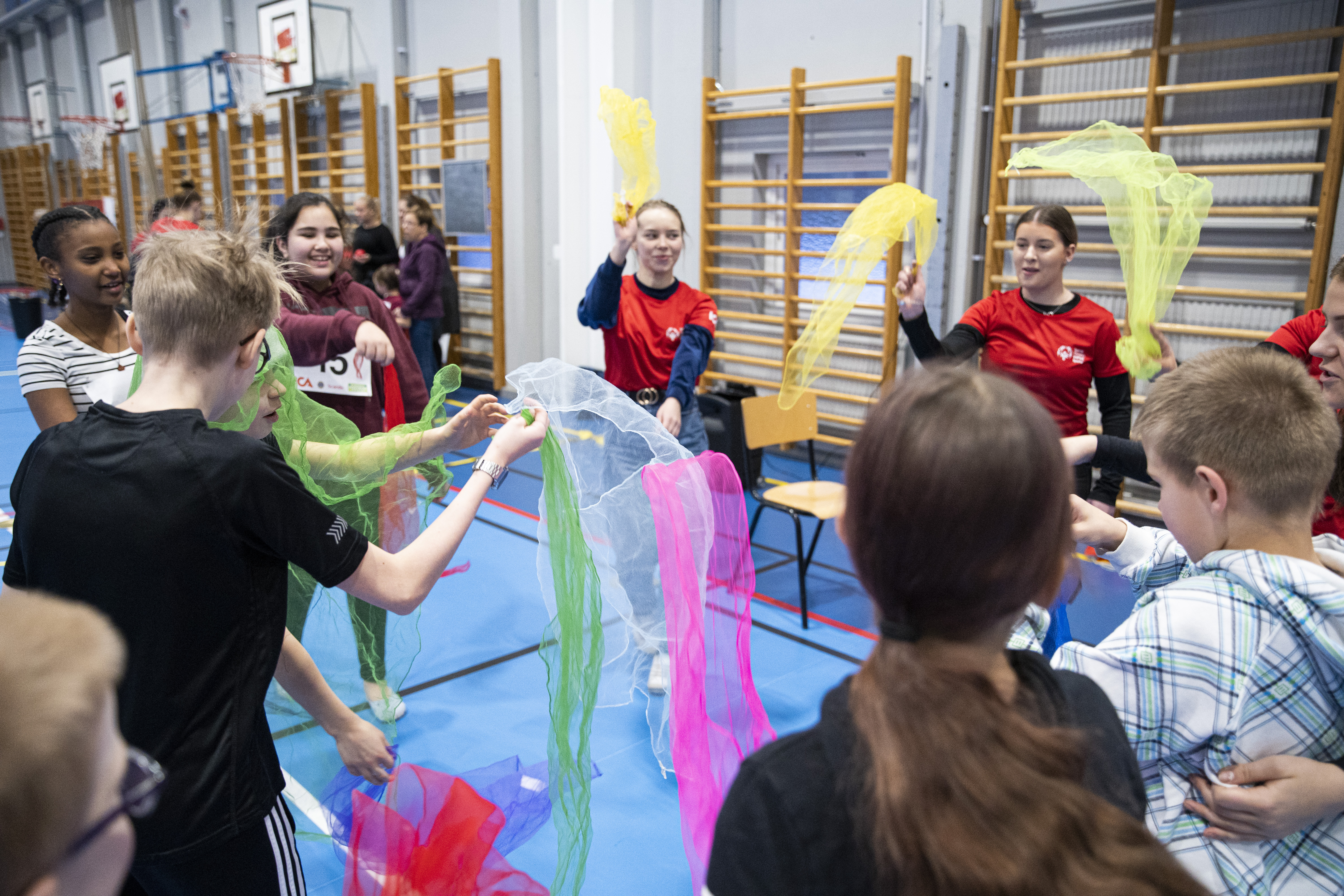En grupp ungdomar viftar med färgglada tyger.