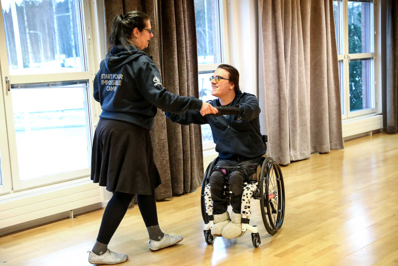En ung man i rullstol dansar med en kvinna utan rullstol.
