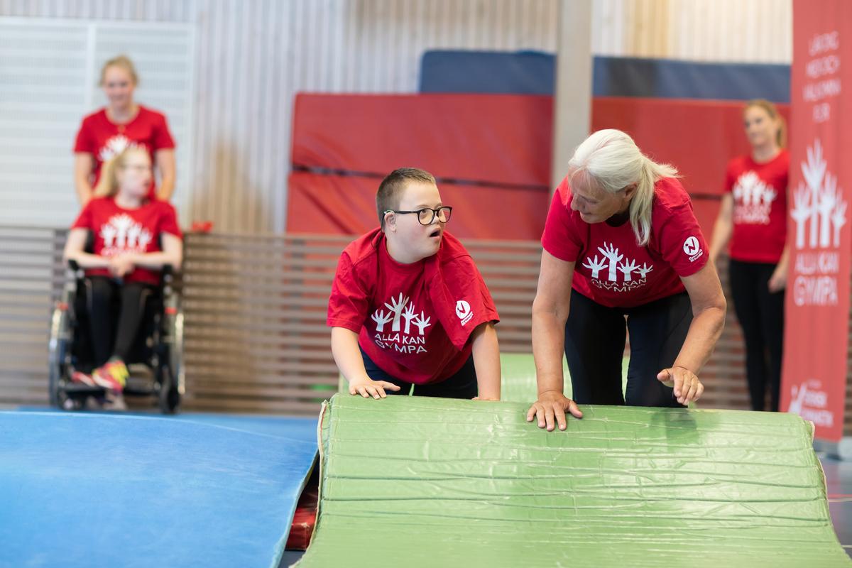 En gymnast och en ledare hjälps åt vid mattan.