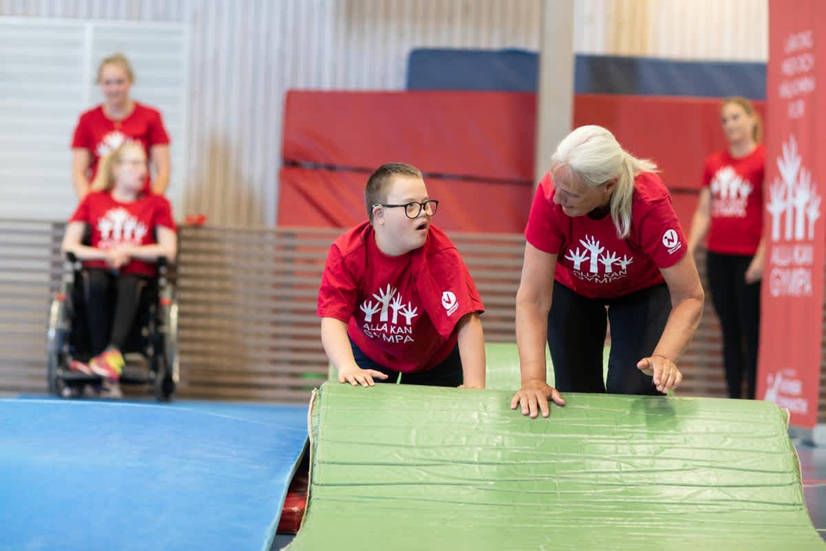 En gymnast och en ledare hjälps åt vid mattan.