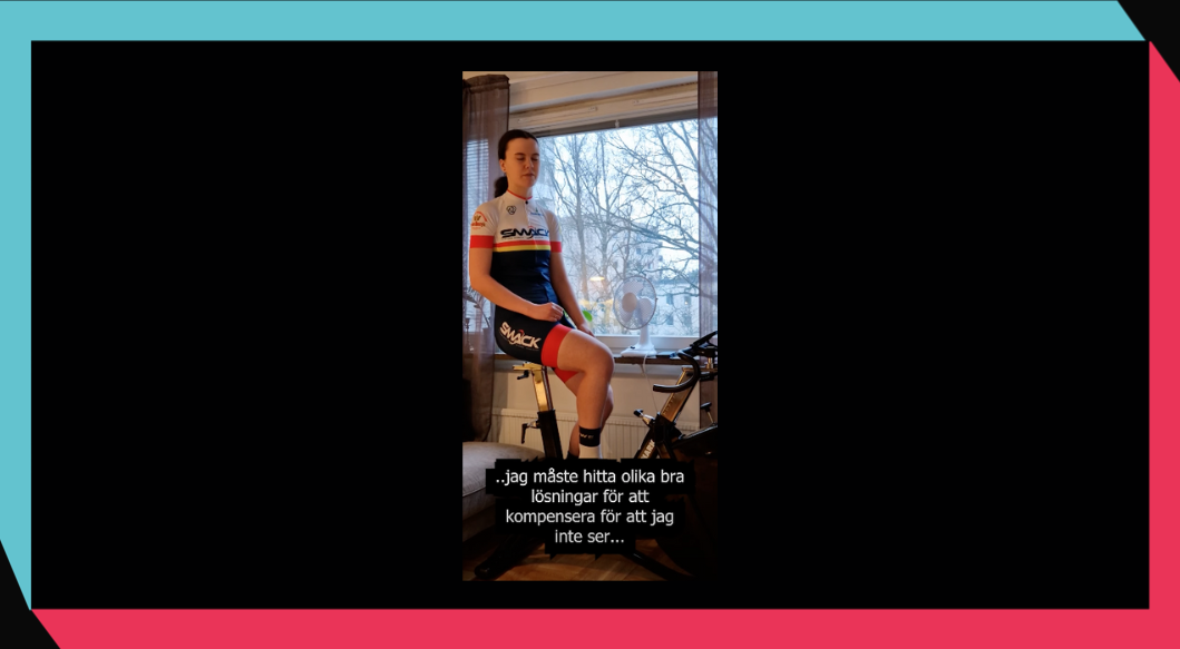 Stillbild från videon med Louise som sitter på en motionscykel i sitt vardagsrum. 