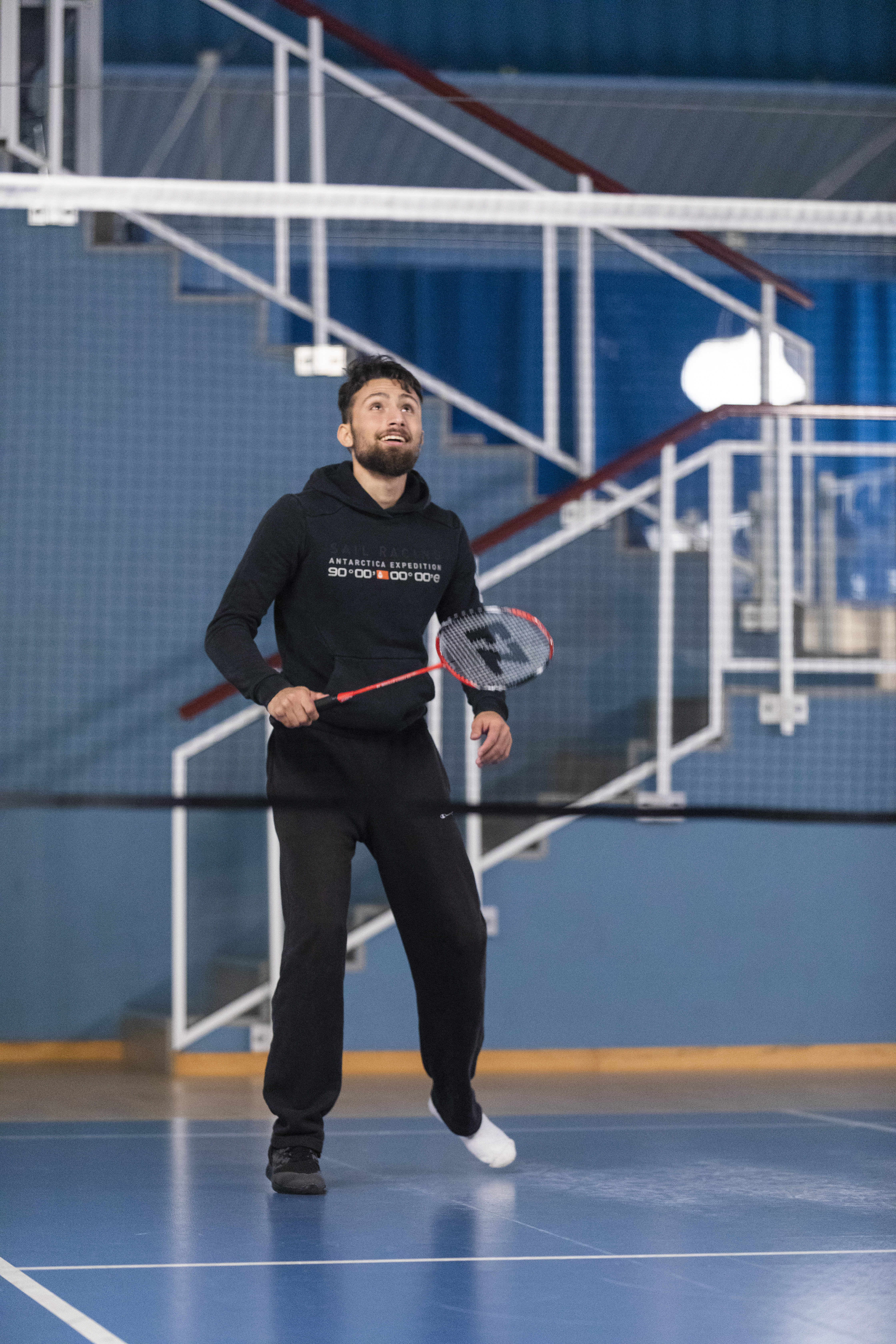 En man står bakom nätet och väntar på att slå iväg badmintonfjädern.