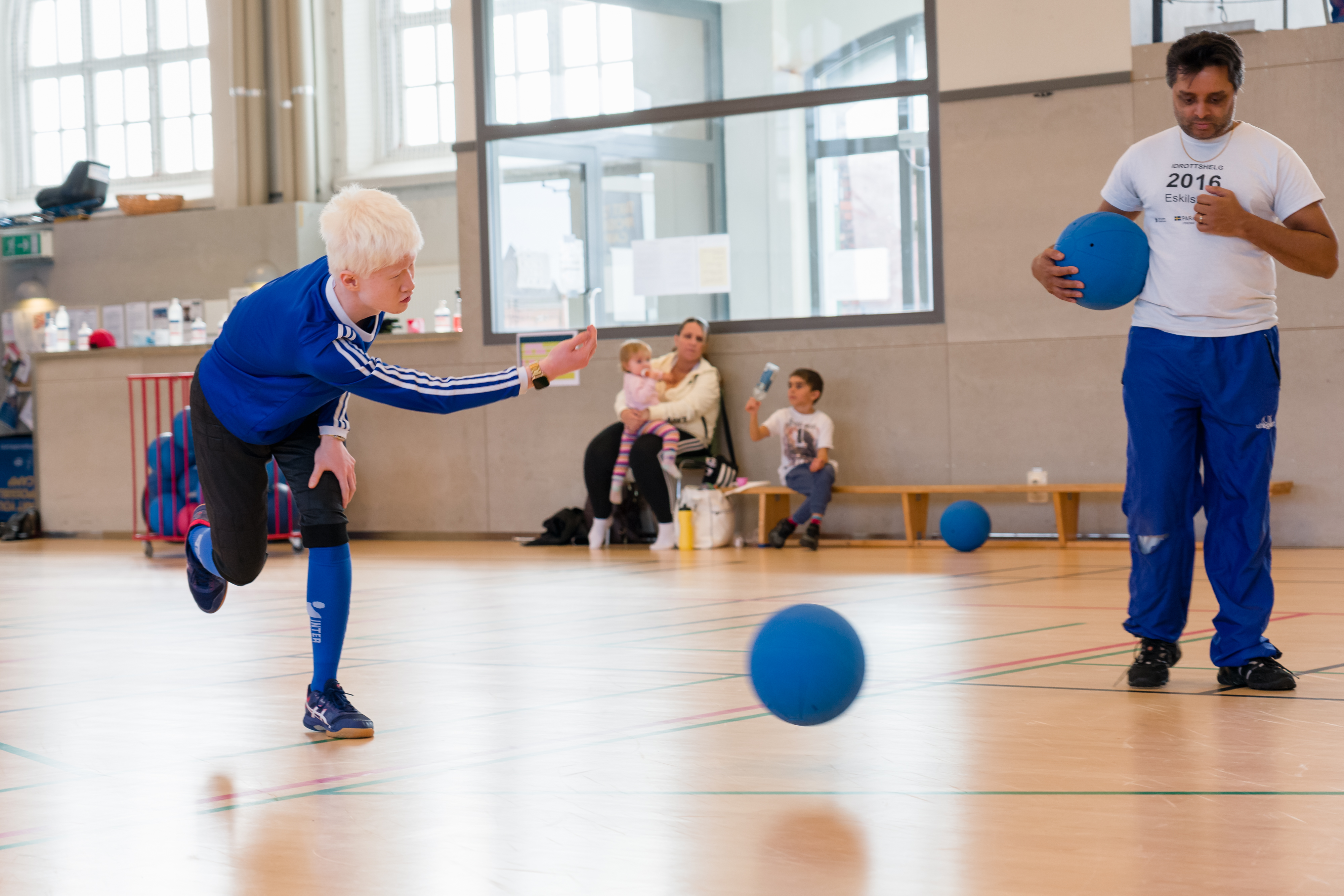 Kille skjuter iväg bollen med högerarmen. Instruktör står bredvid.