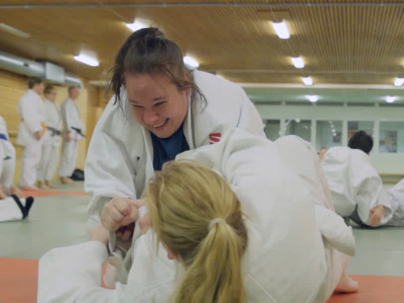 Två kvinnor i judodräkter brottas på mattan.