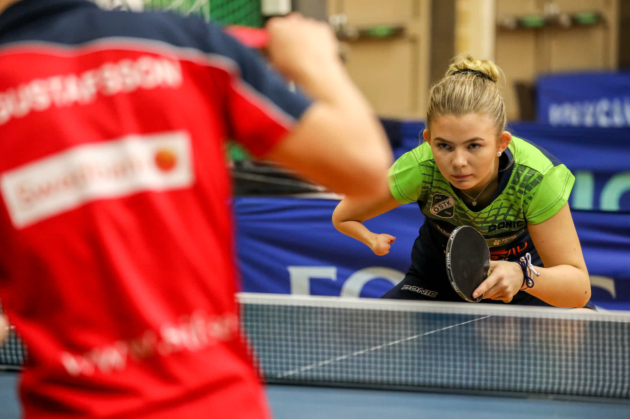 Ung kvinna spelar bordstennismatch och väntar på motståndarens serve.