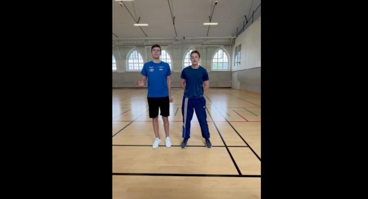 Inomhusmiljö, idrottshall. Felix och Arvid står bredvid varandra mitt på hallgolvet.