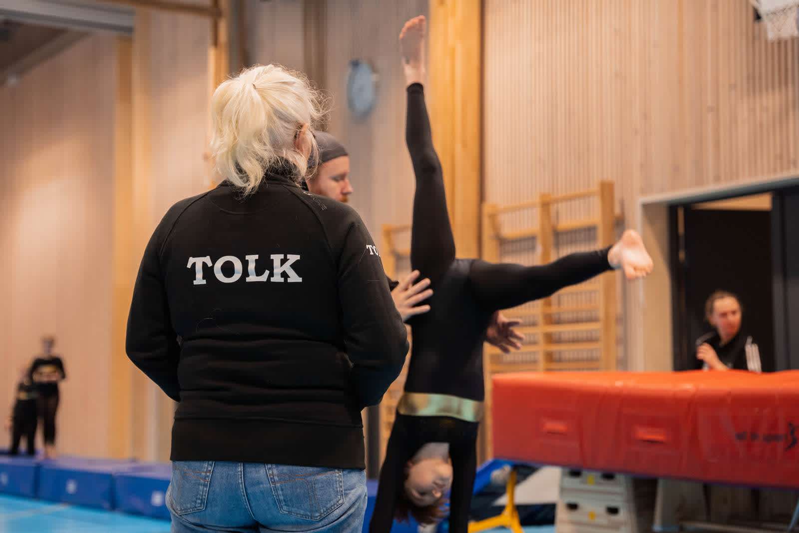 En gymnast får hjälp av en ledare när hon gör en volt.