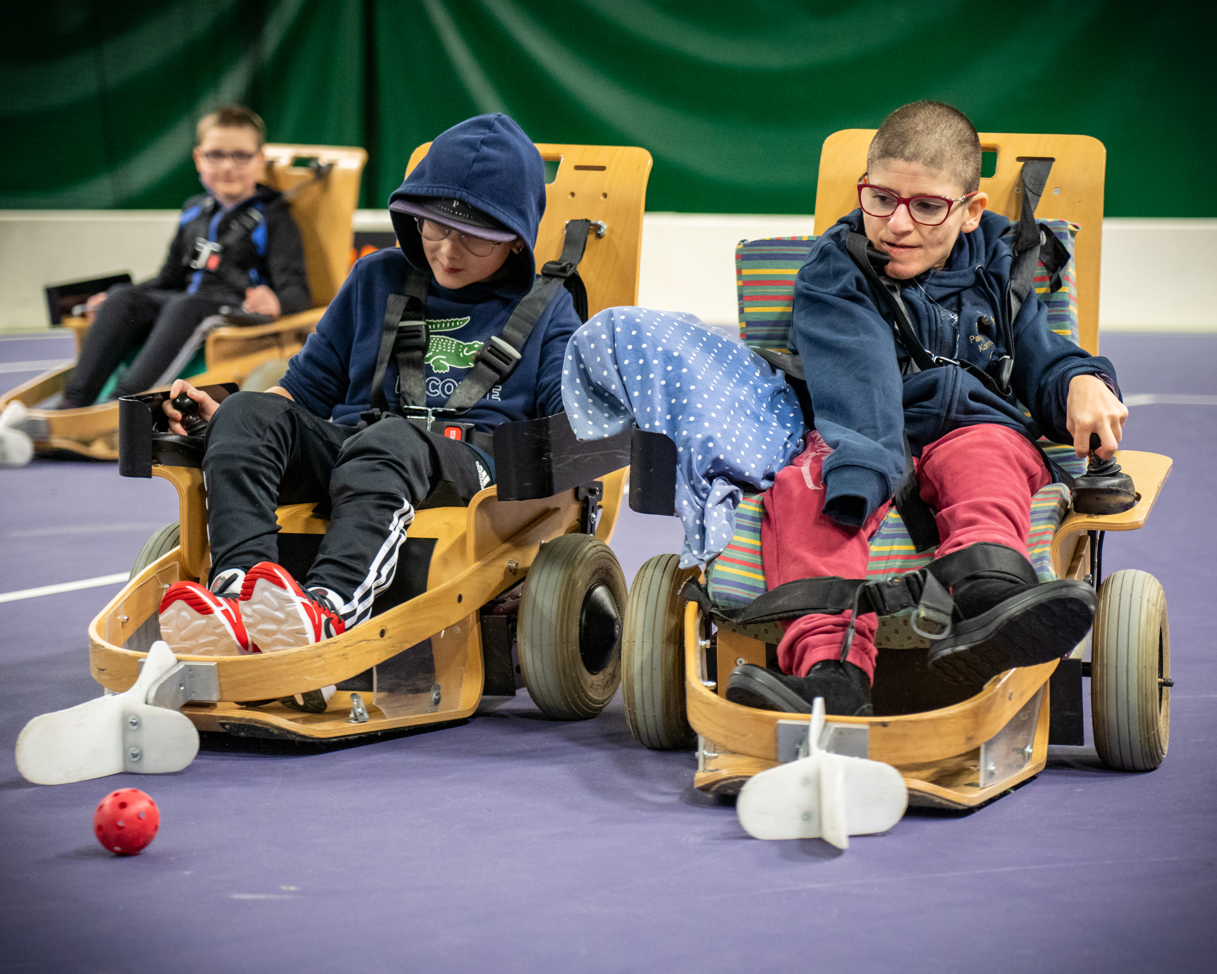 Två pojkar i elinnebandystol försöker komma först till bollen.
