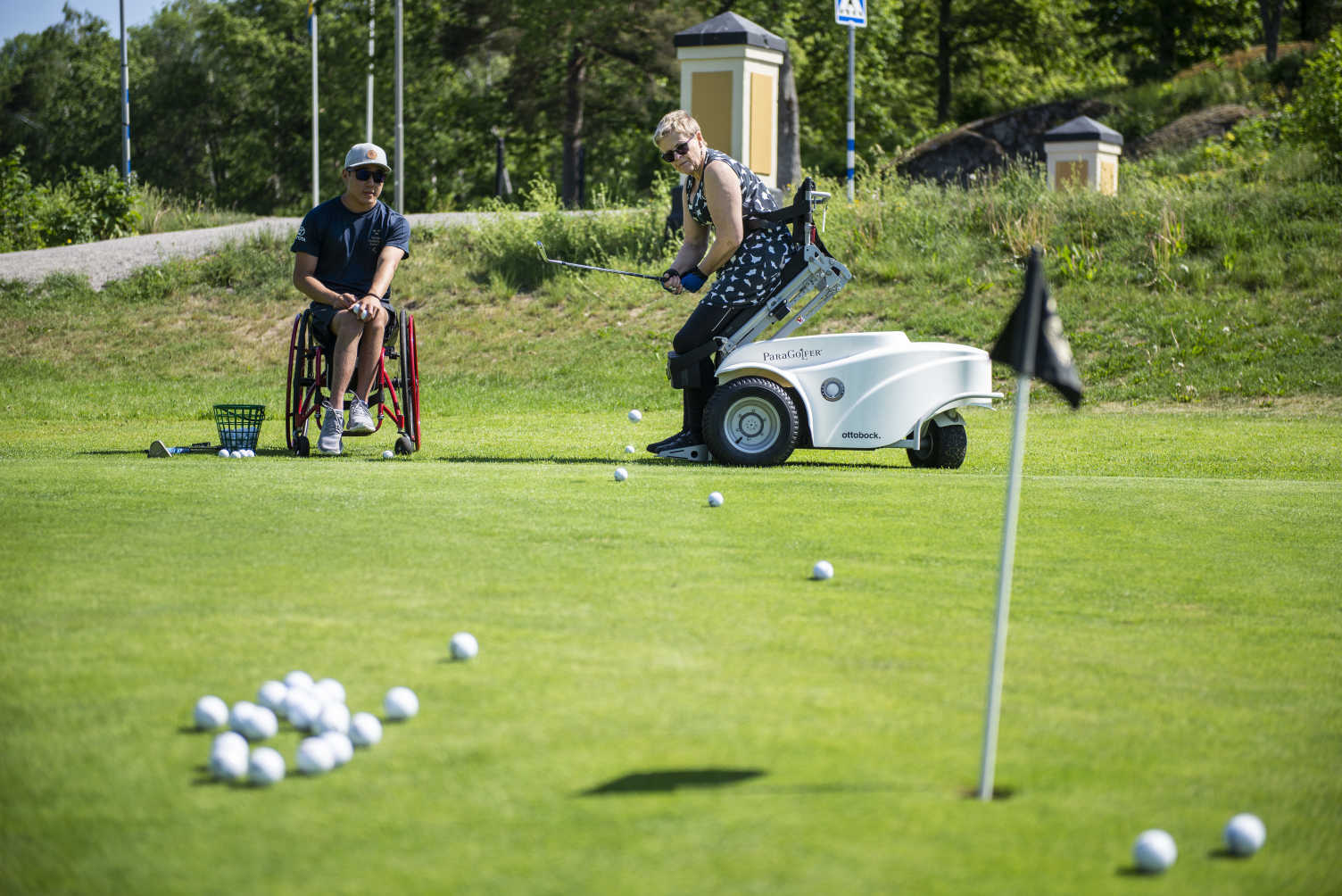 Två golfspelare i rullstolar övar på att putta.