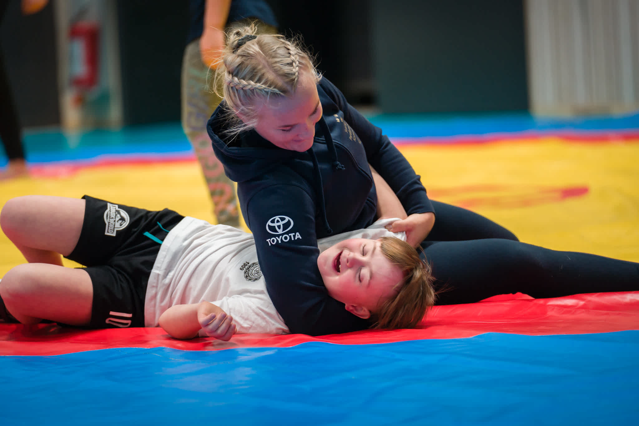 En glad, skrattande pojke ligger på rygg, nedbrottad av en instruktör.