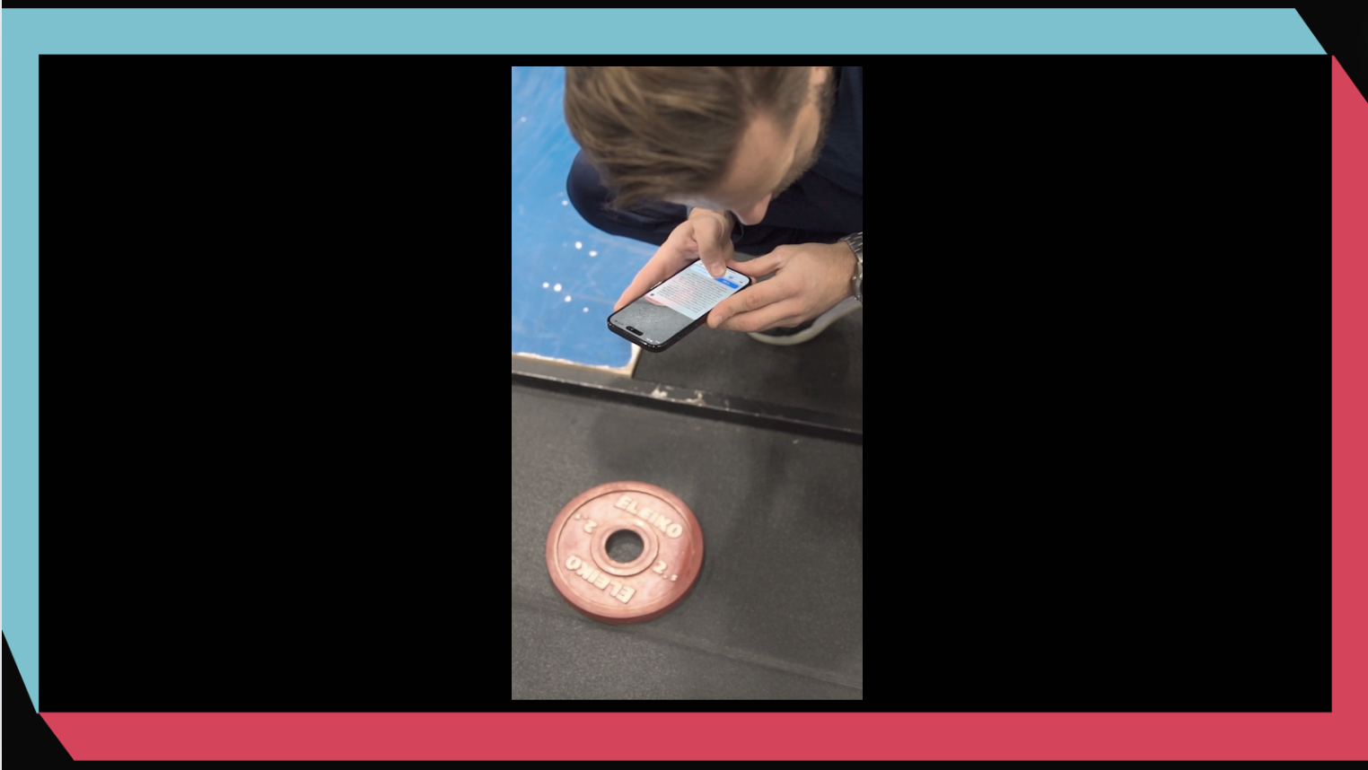 Man som med sin telefon tar en bild på en viktskiva på golvet. Blå och rosa ram runt.