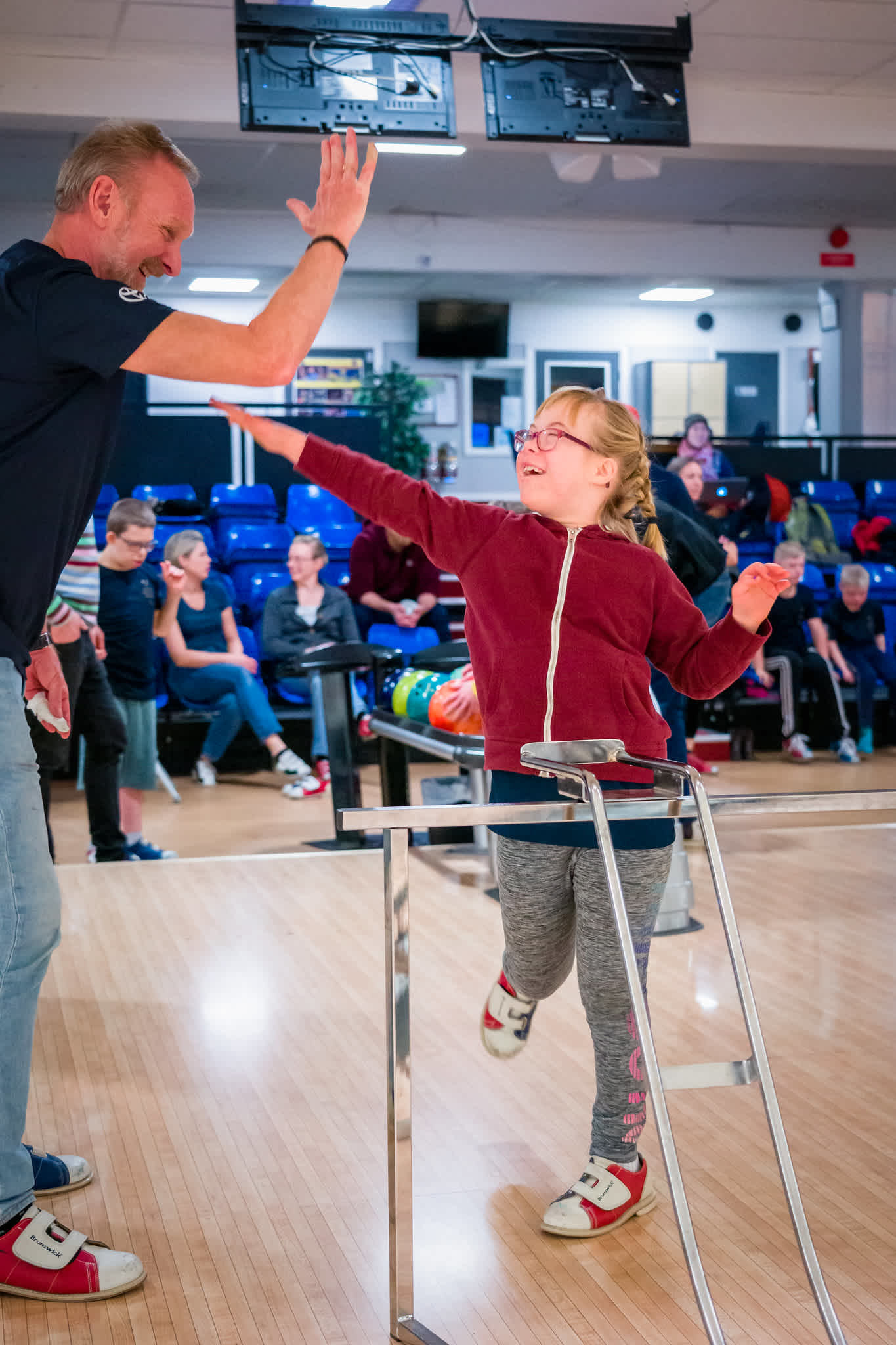 Flicka gör high five med instruktören efter ett lyckat bowlingkast.