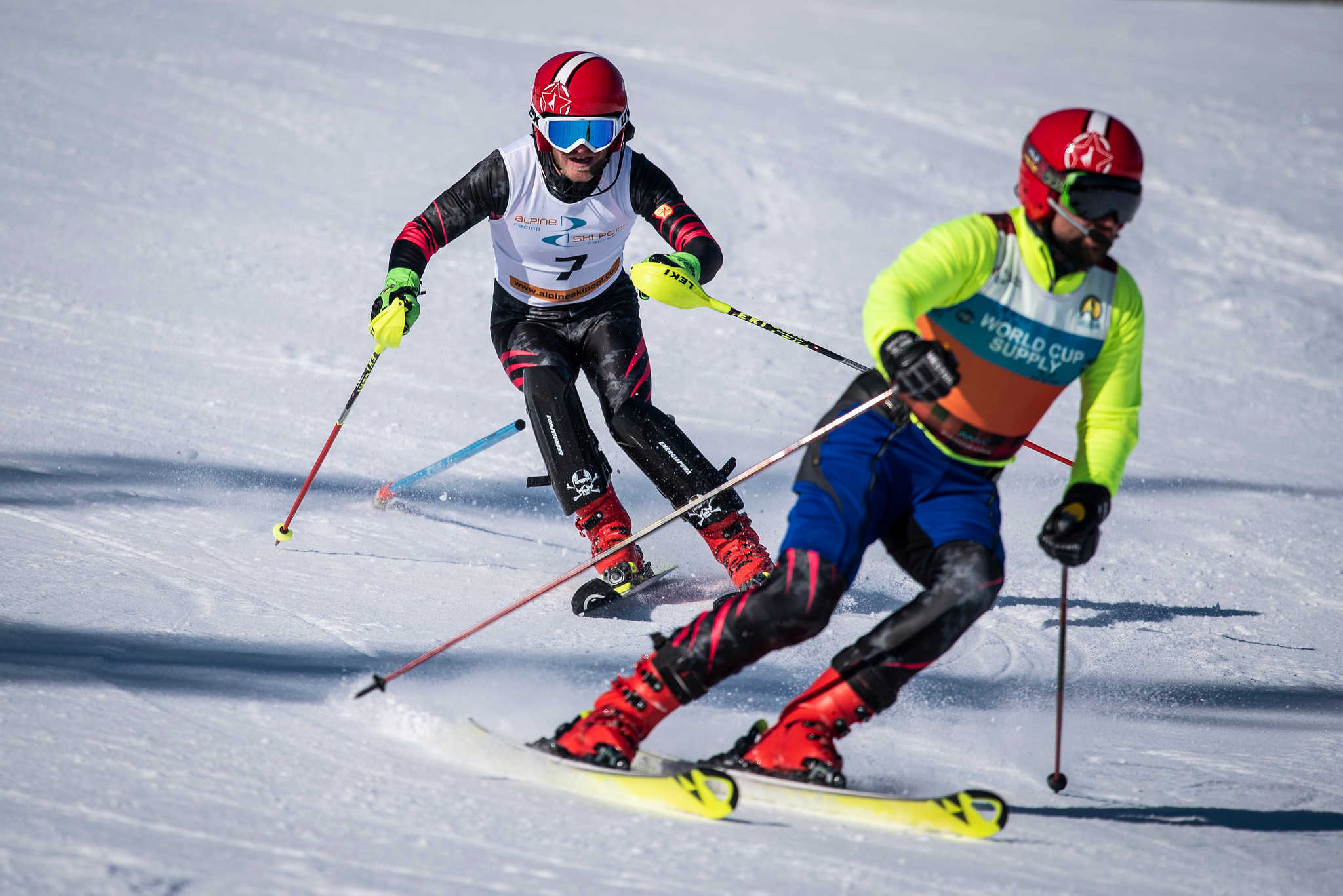 En man med synnedsättning åker slalom och följer en guide som visar vägen.