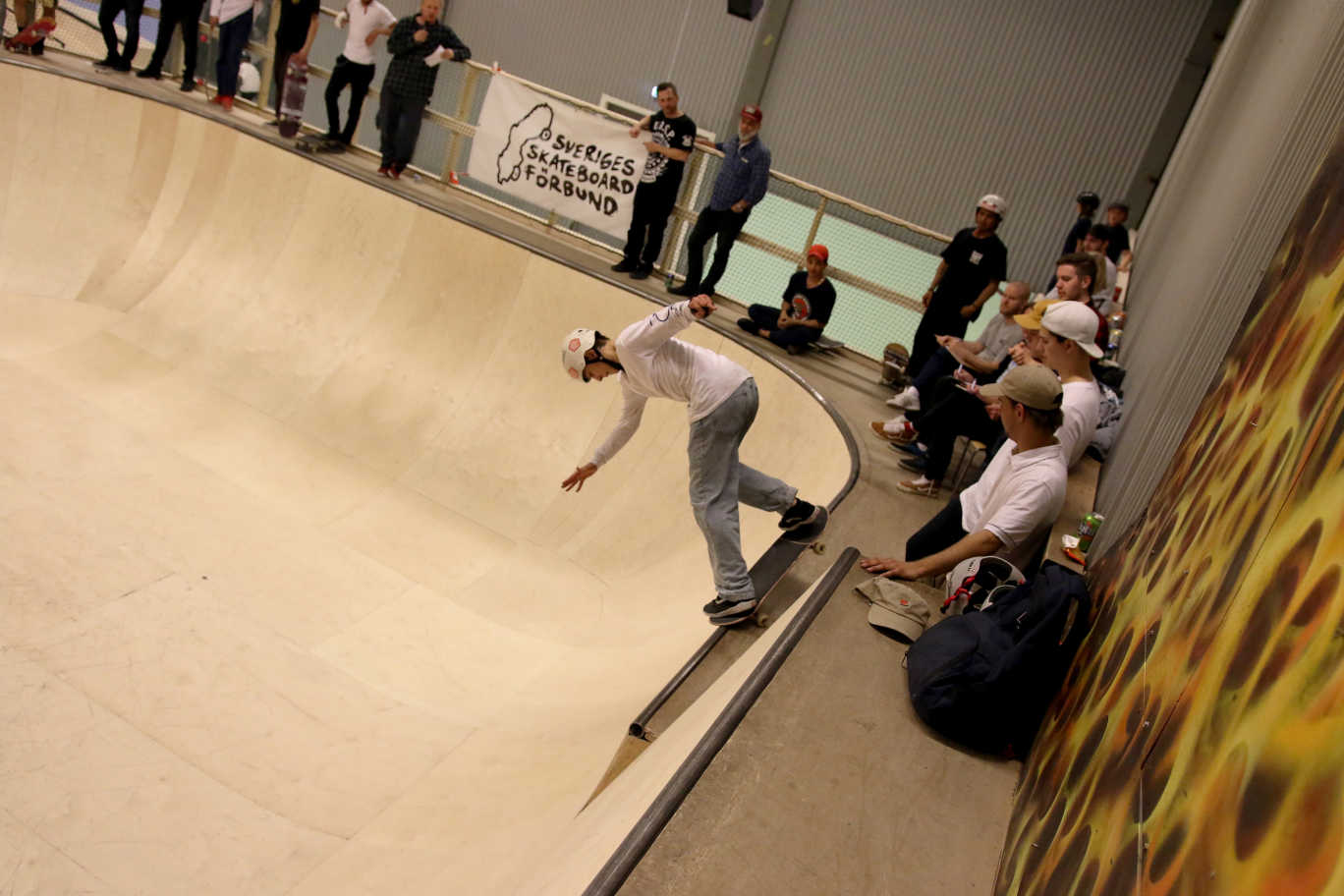 En kille står på skateboarden och är på väg ner i rampen. 