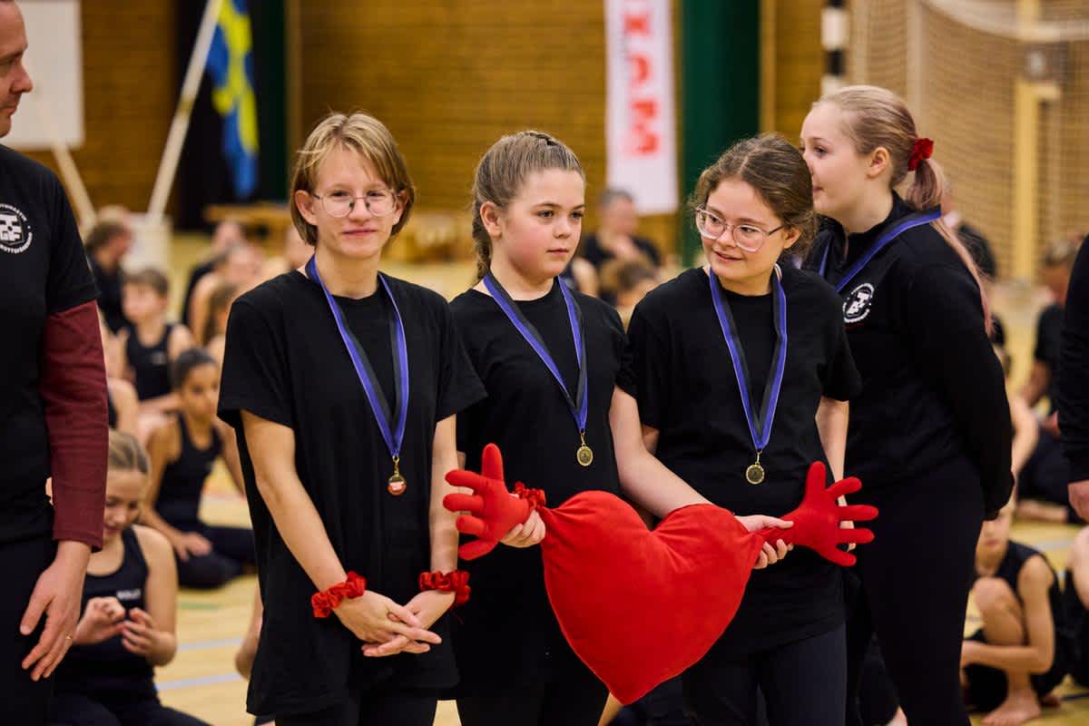 Flera gymnaster har fått medalj och håller i ett mjukis-hjärta.
