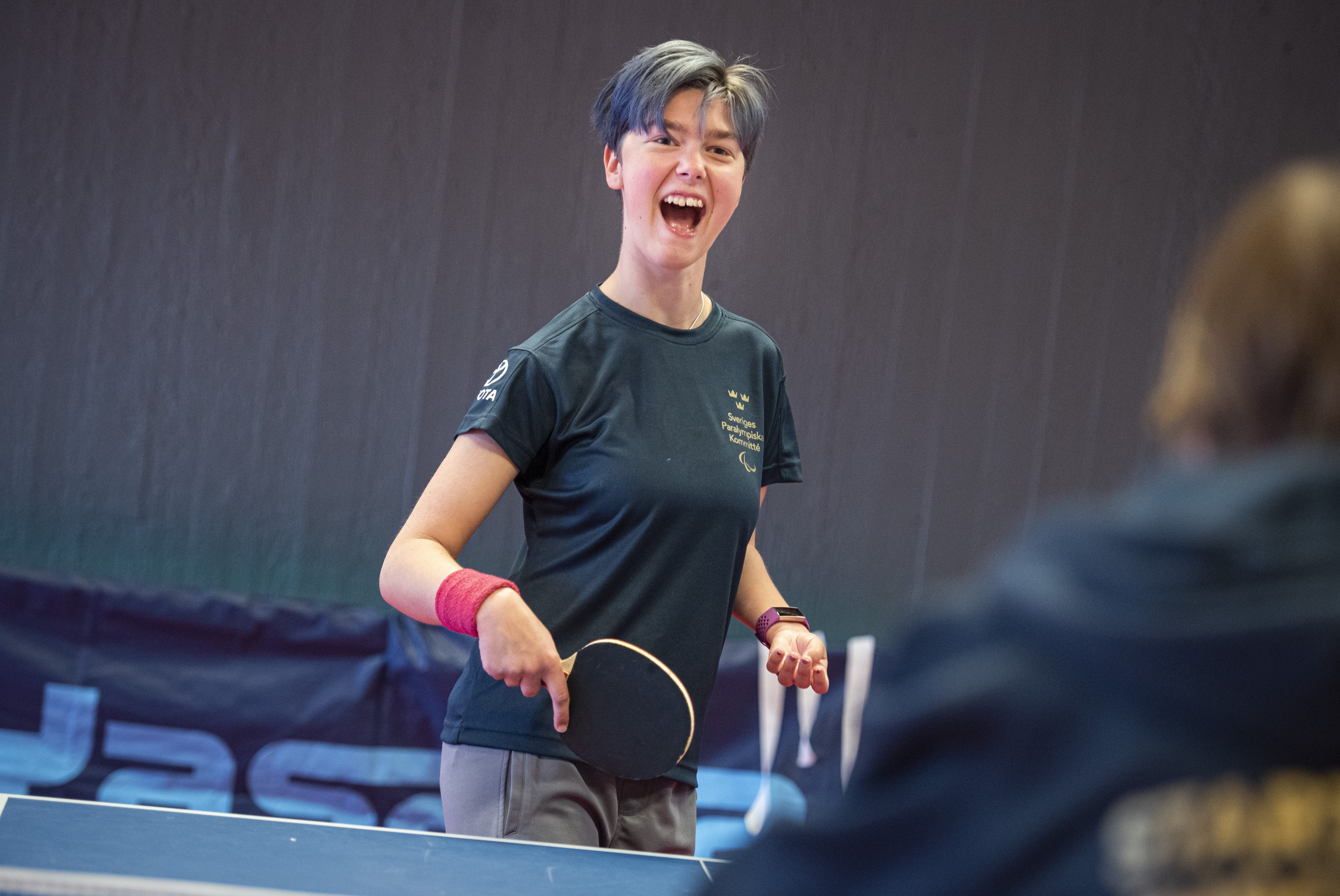 Två glada personer spelar bordtennis tillsammans.