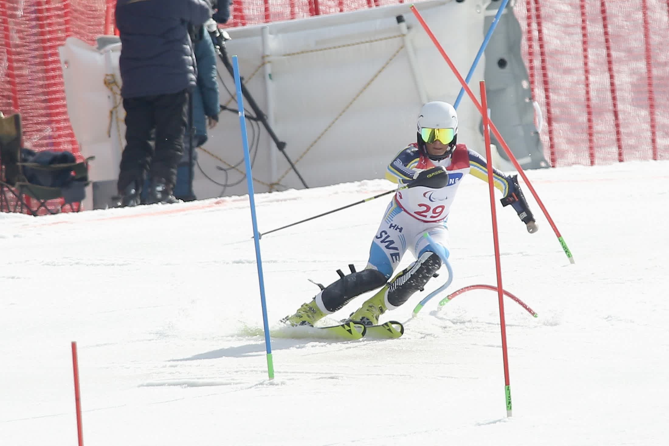 En person tävlar i slalomåkning och passerar slalomkäppar i skidbacken.