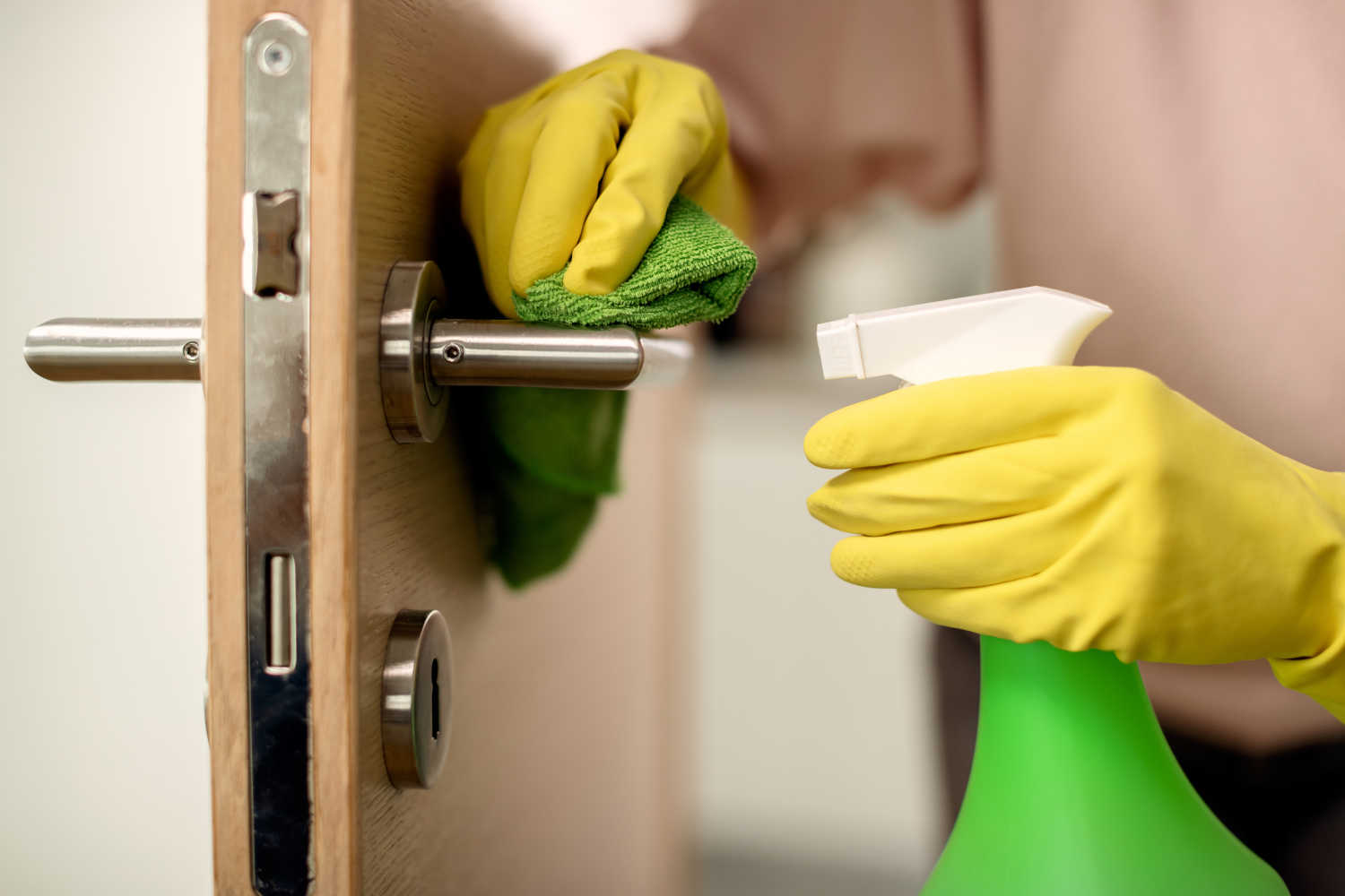 cloeup-woman-disinfecting-door-handle-home