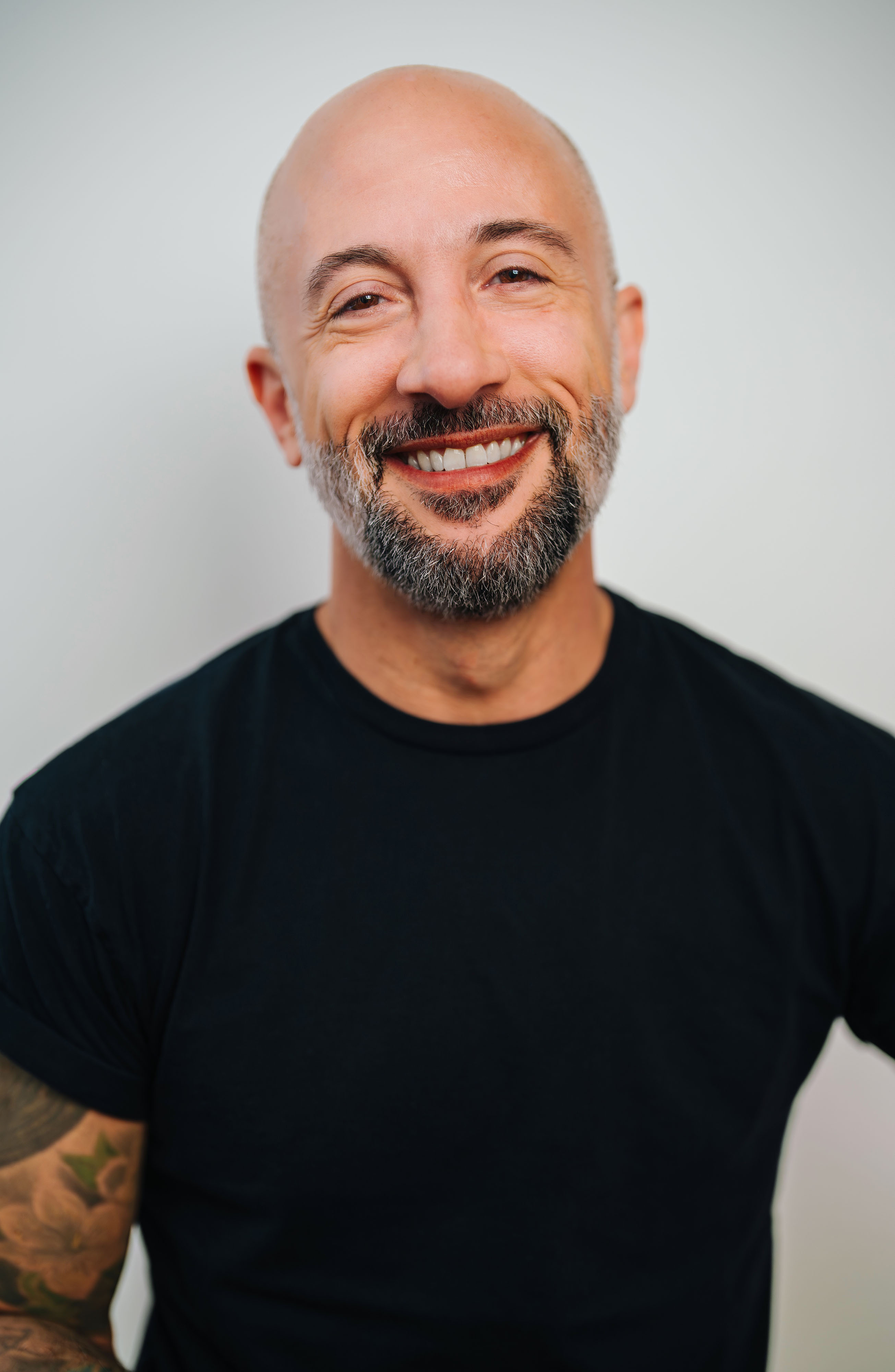 Jules Rosskam headshot. A bald and bearded white masculine presenting person smiles wide for camera.