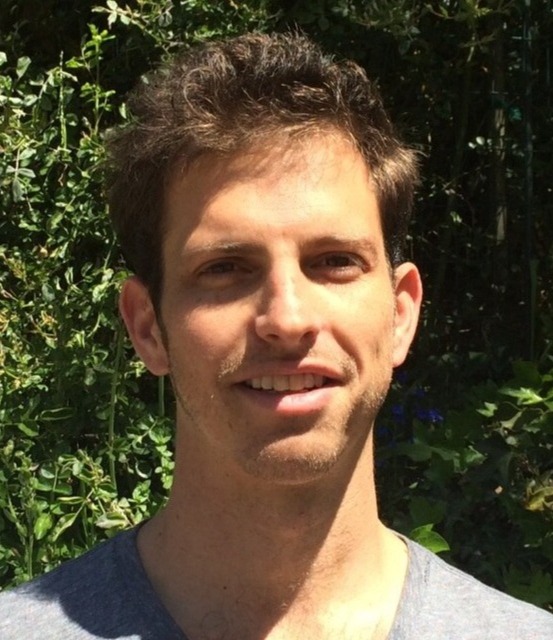 A portrait of a man on a sunny day smiling and looking into the camera.