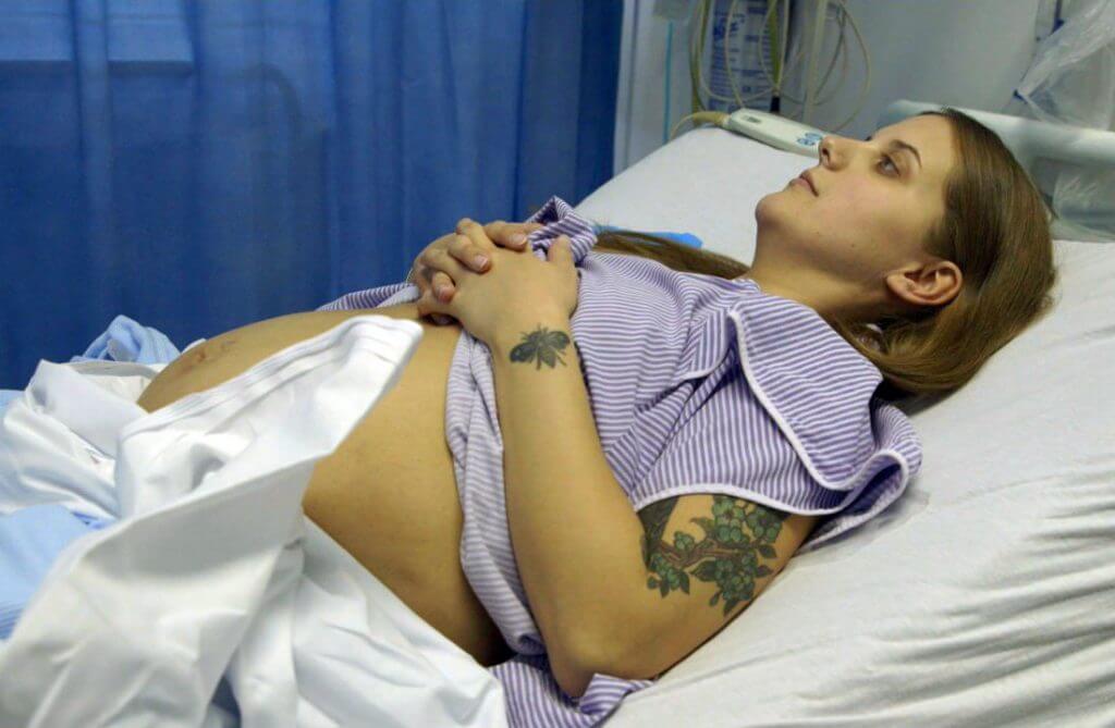 Still from Is There Anybody Out There? Ella Glendining is on a a medical bend with her belly uncovered