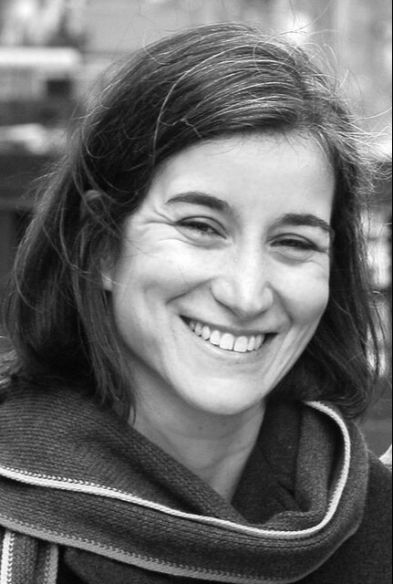 Producer Yael Melameade looking directly at camera and smiling. Black and white photo.