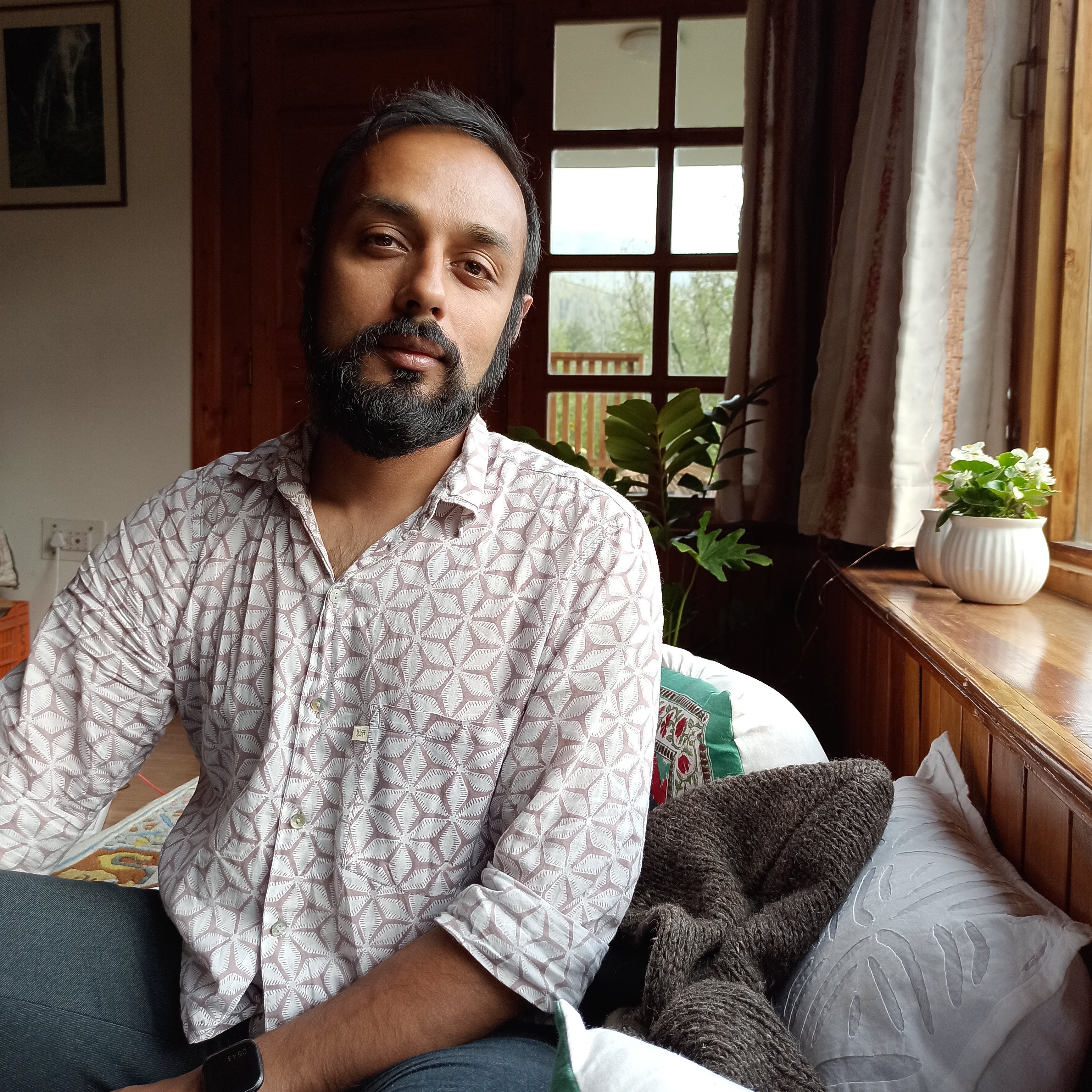 Sushmit Ghosh looks directly at the camera and smiles. He wears a white blouse.