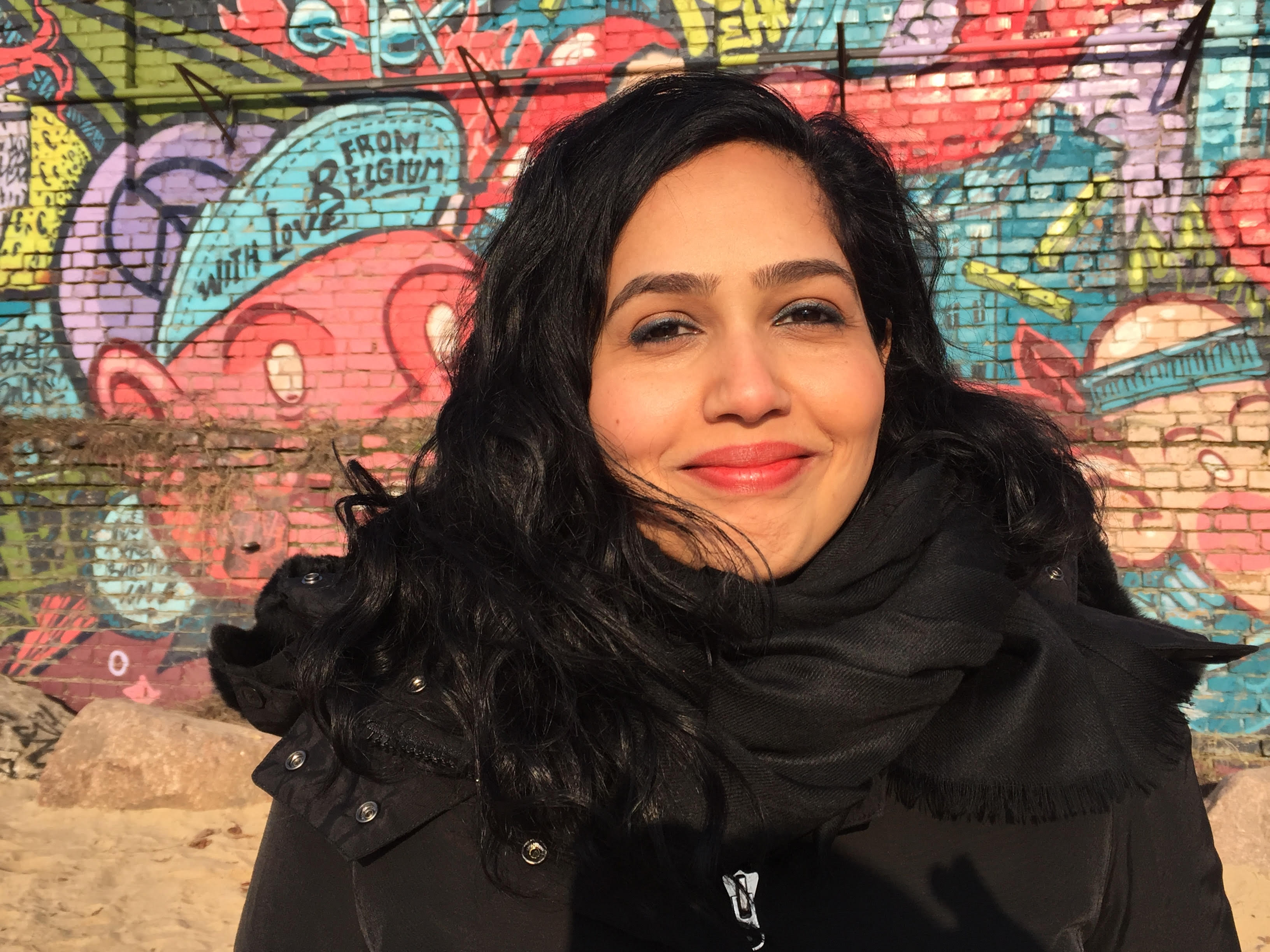 Nausheen Dadabhoy smiling at the camera. She has medium-length wavy hair, and wears a winter jacket and scarf. 