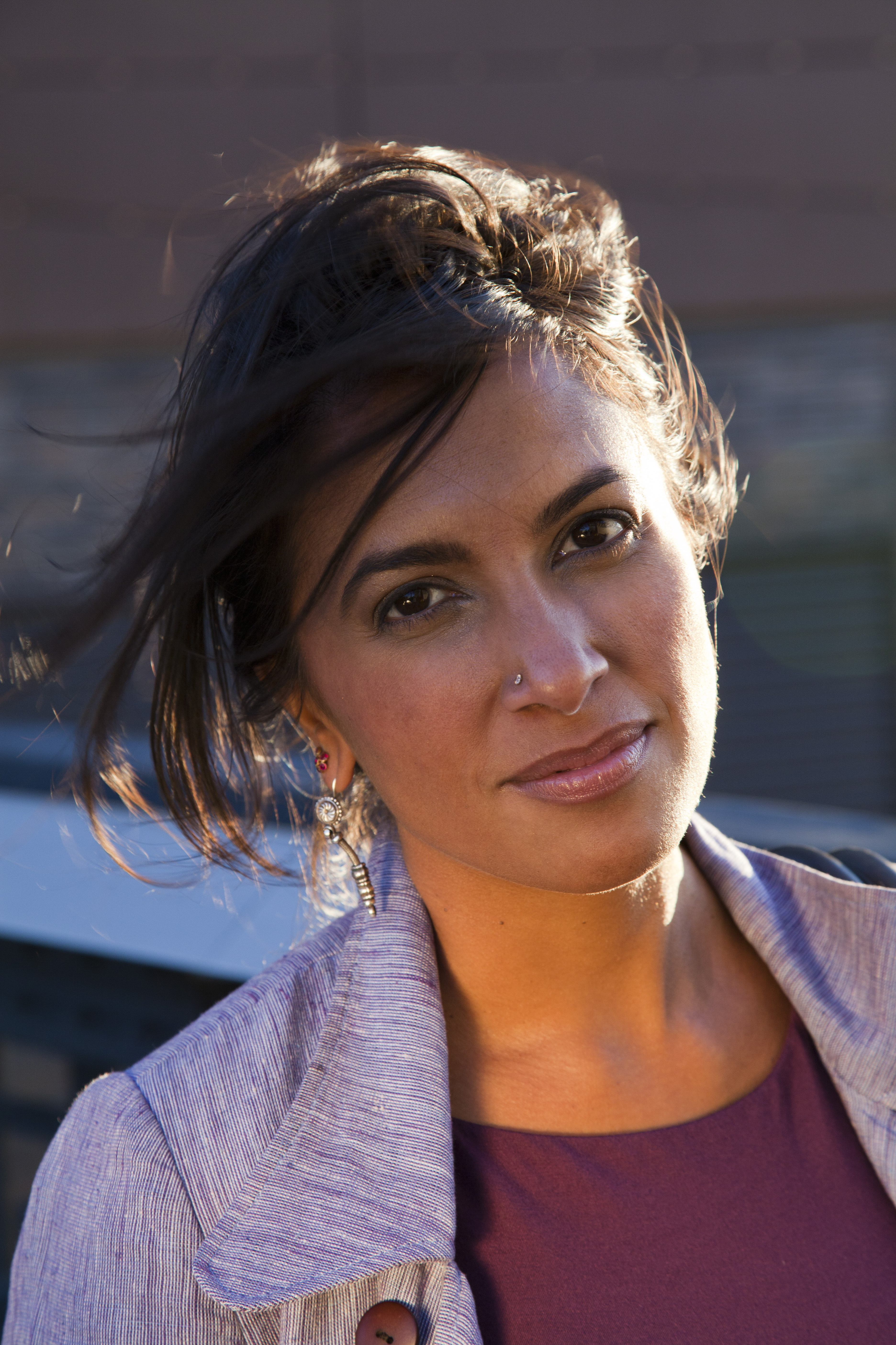 Shalini Kantayya looks directly at the camera and smiles. The wind blows her hair. 