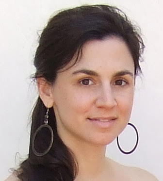 Headshot of Alexandra (Ali) Codina from the neck up with a slightly open mouth smile wearing hoop earrings.