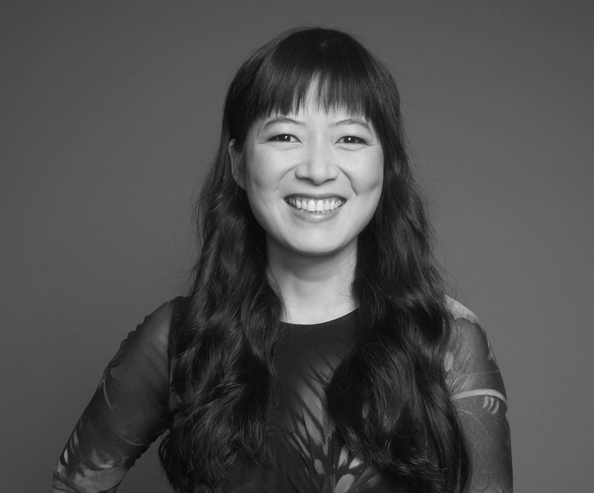 Jialing Zhang looking directly ahead and smiling. She has long, dark hair and bangs. Black and white portrait.