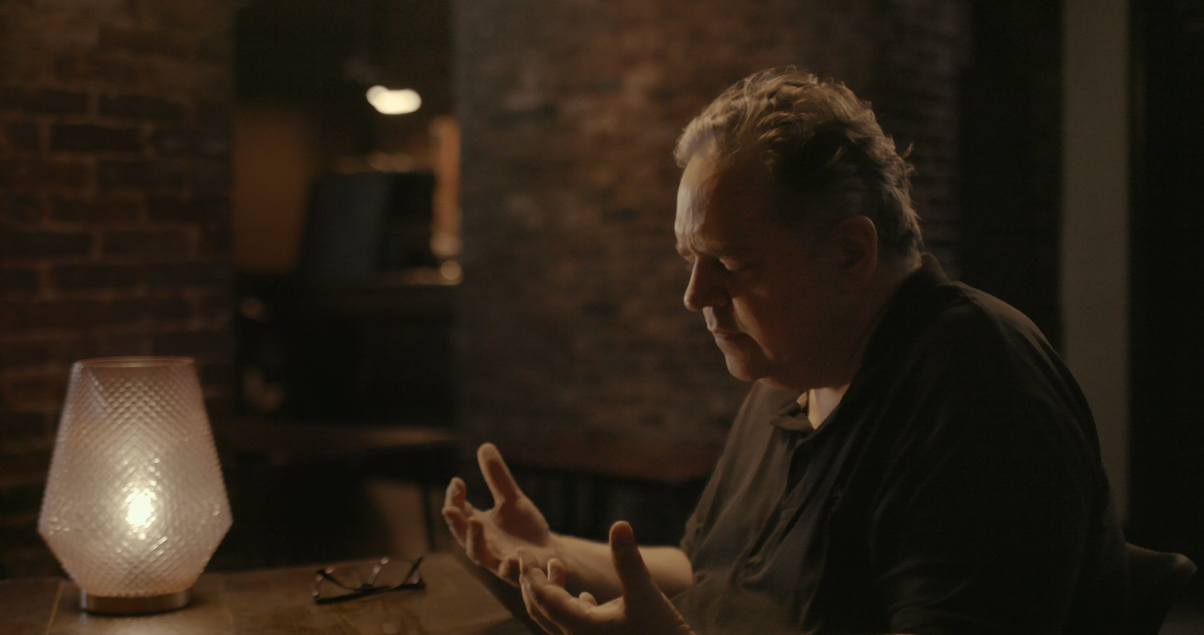 Still from Look Into My Eyes. A psychic man closes his eyes with his hands out in front of him.