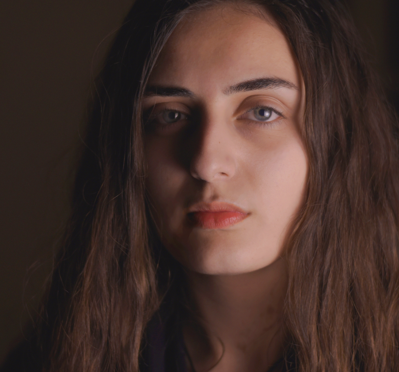 A portrait of Hazar Yazji against a brown background.